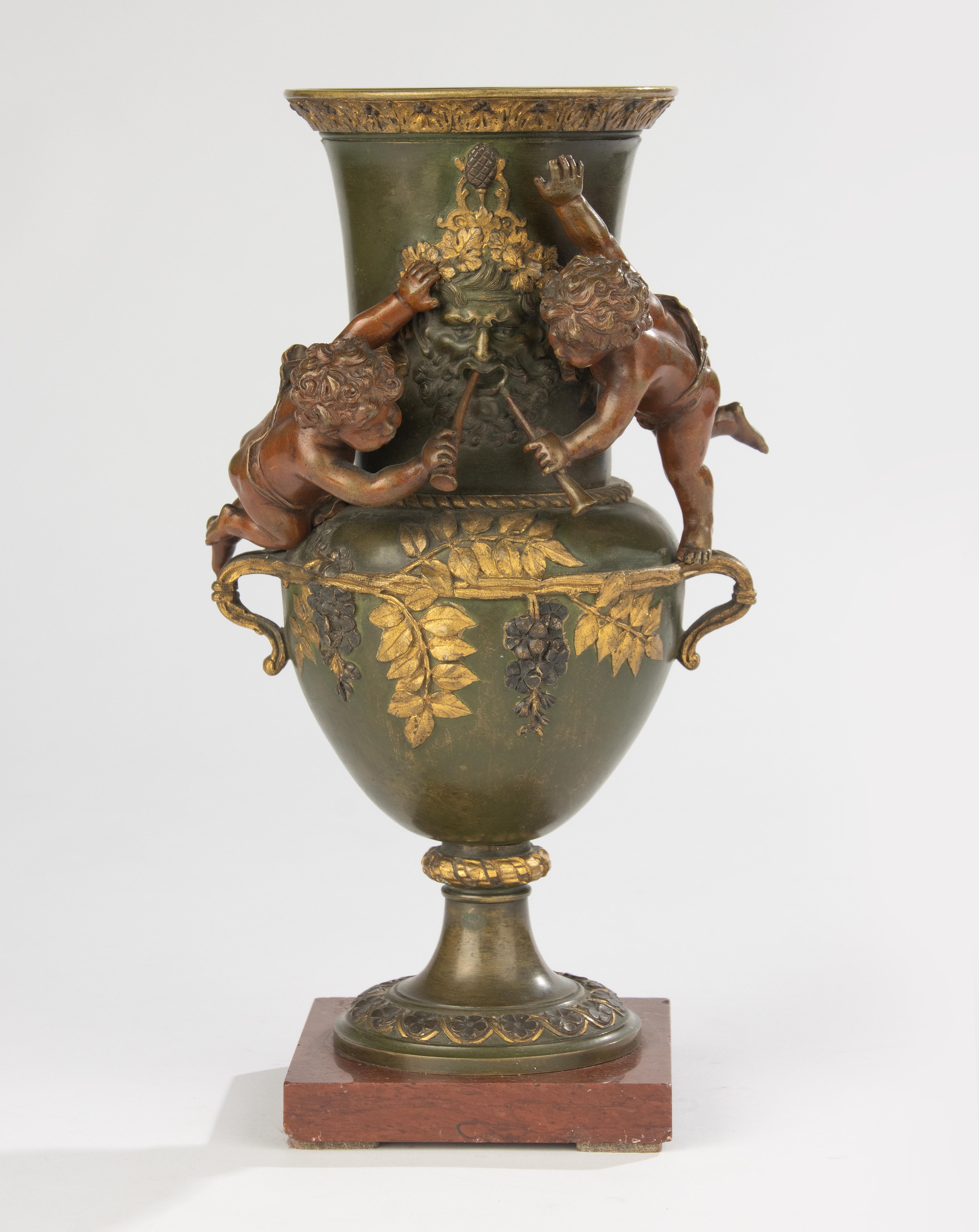 Elegant 19th century bronze coupe mounted on a square marble base. This refined work features a charming scene of two cherubs in high relief, set against a rich decoration of vine leaves and grapes, with a central mask of Bacchus. The detailed