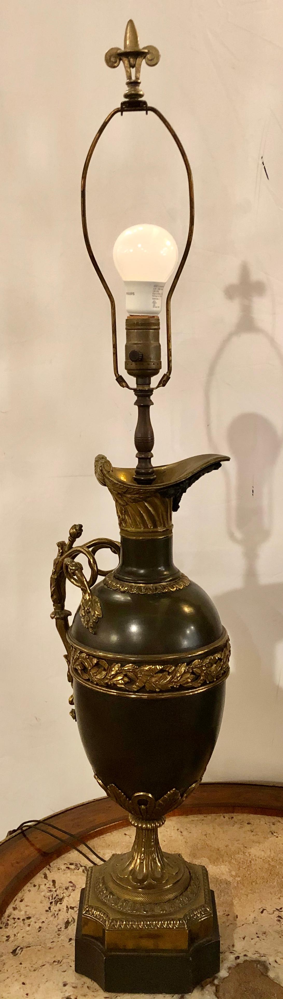 19th century bronze ewer urn form table lamps. A pair of Louis XVI style neoclassical fashioned table lamps having a wreath flanking a bearded man. The whole marble bases. Each take a single sixty watt bulb. No shades.