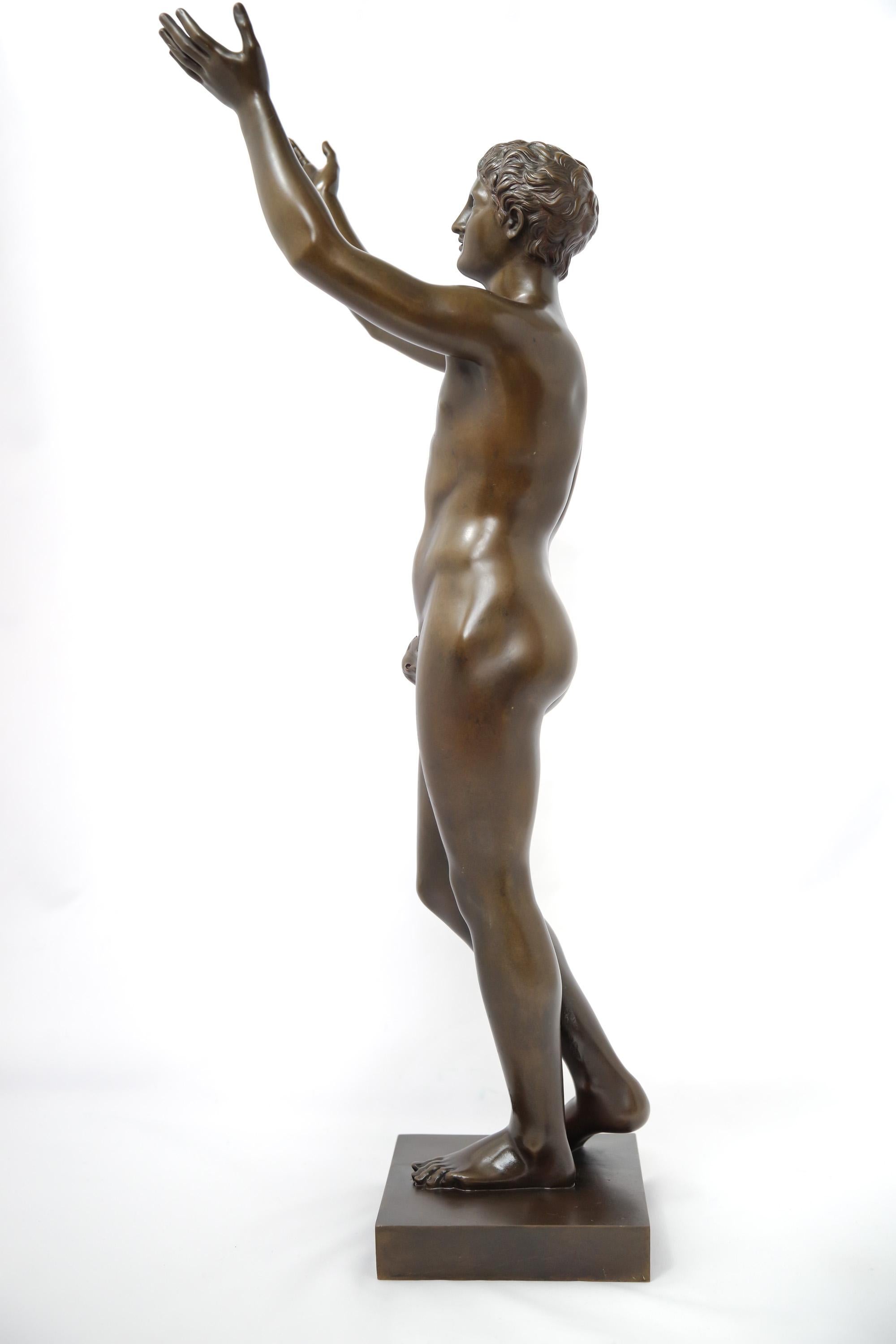 A 19th-century patinated bronze figure of the Berlin Adorante, or Praying Boy. The piece is a reduction of the Hellenistic-era original, currently in the Altes Museum in Berlin, by Lysippos or his circle. It depicts a boy standing on his left foot,