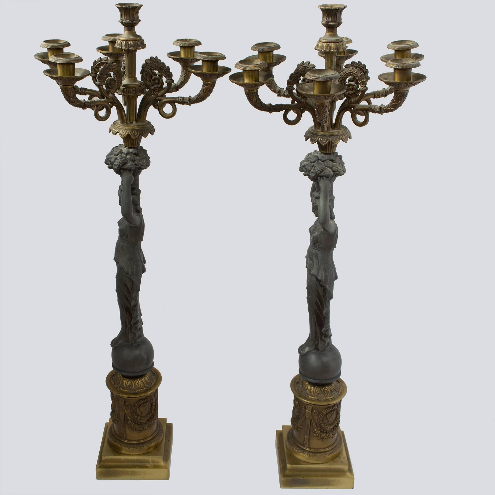 About
Pair of 19th century bronze candelabras with beautiful details, featuring six arms and centre lights, in gilt bronze. The pair features Grecian goddesses with fascinating draping in details each holding an abundant basket atop their heads.