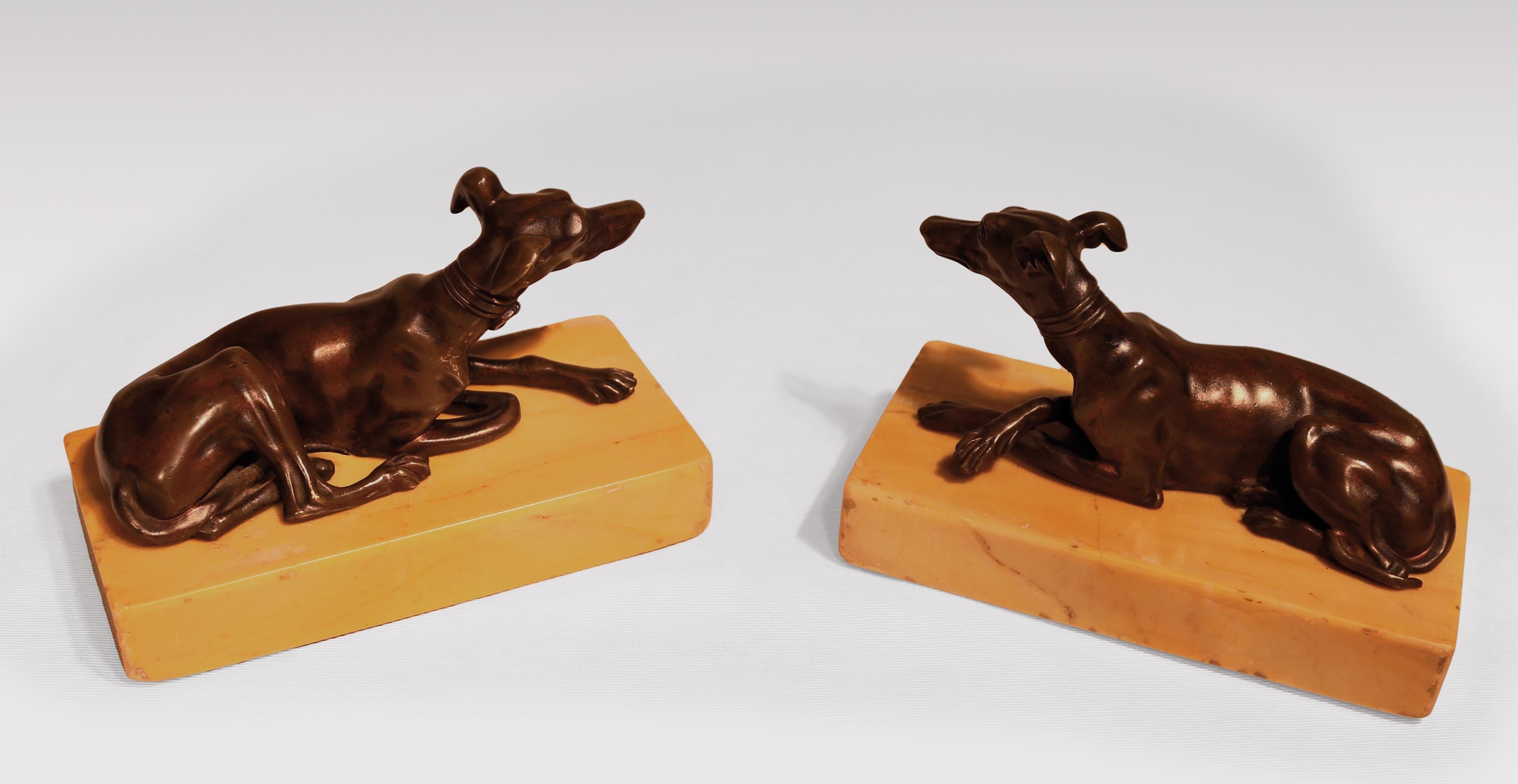A pair of early 19th century well cast models of seated greyhounds with collars supported on Sienna marble bases.