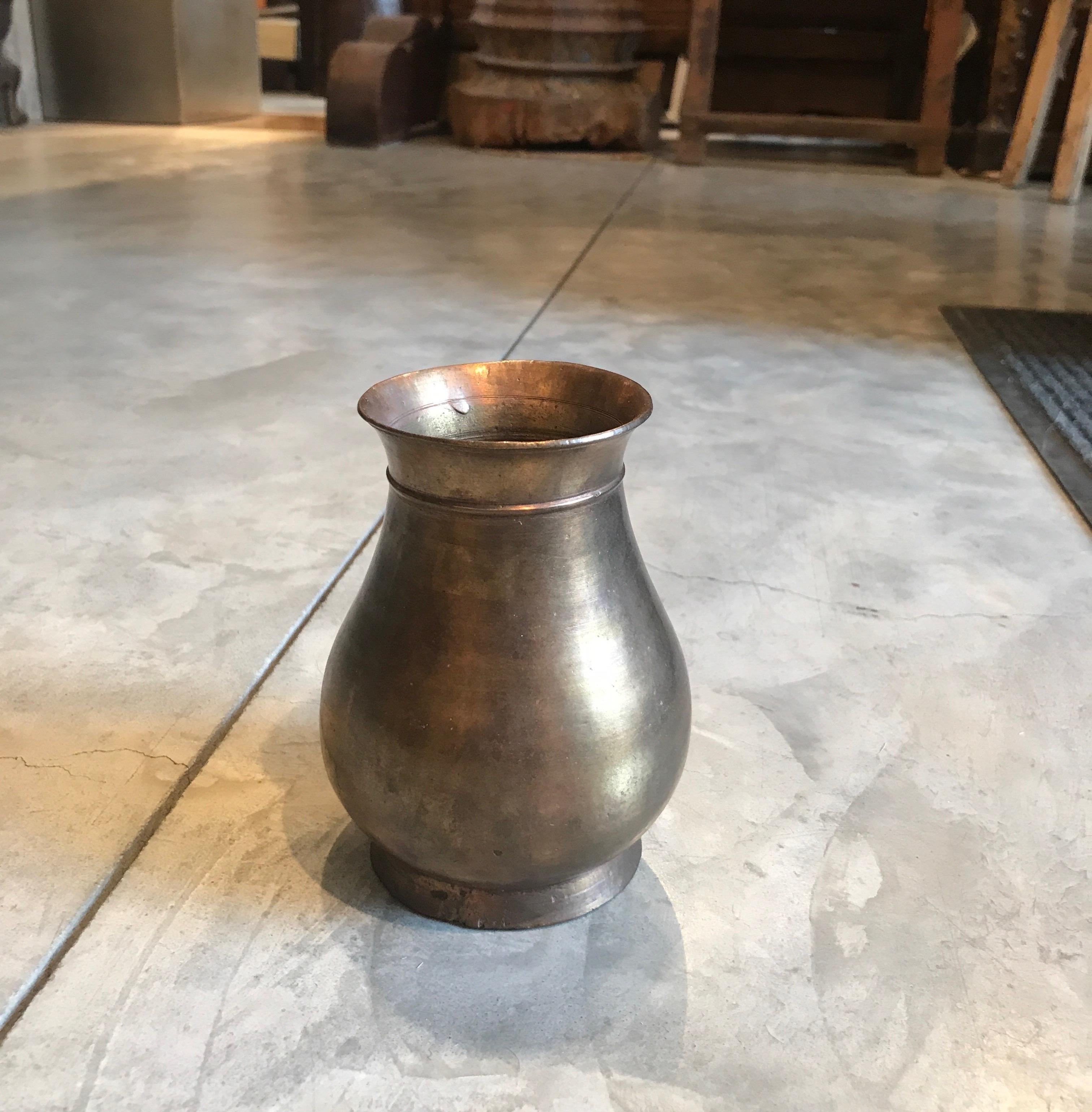 A late 19th Century cast bronze holy water decanter from Nepal. This spiritual object has a truly striking surface, the product of years of handling as part of Buddhist rituals. With clean lines and just a simple decoration near the lip of the jar,