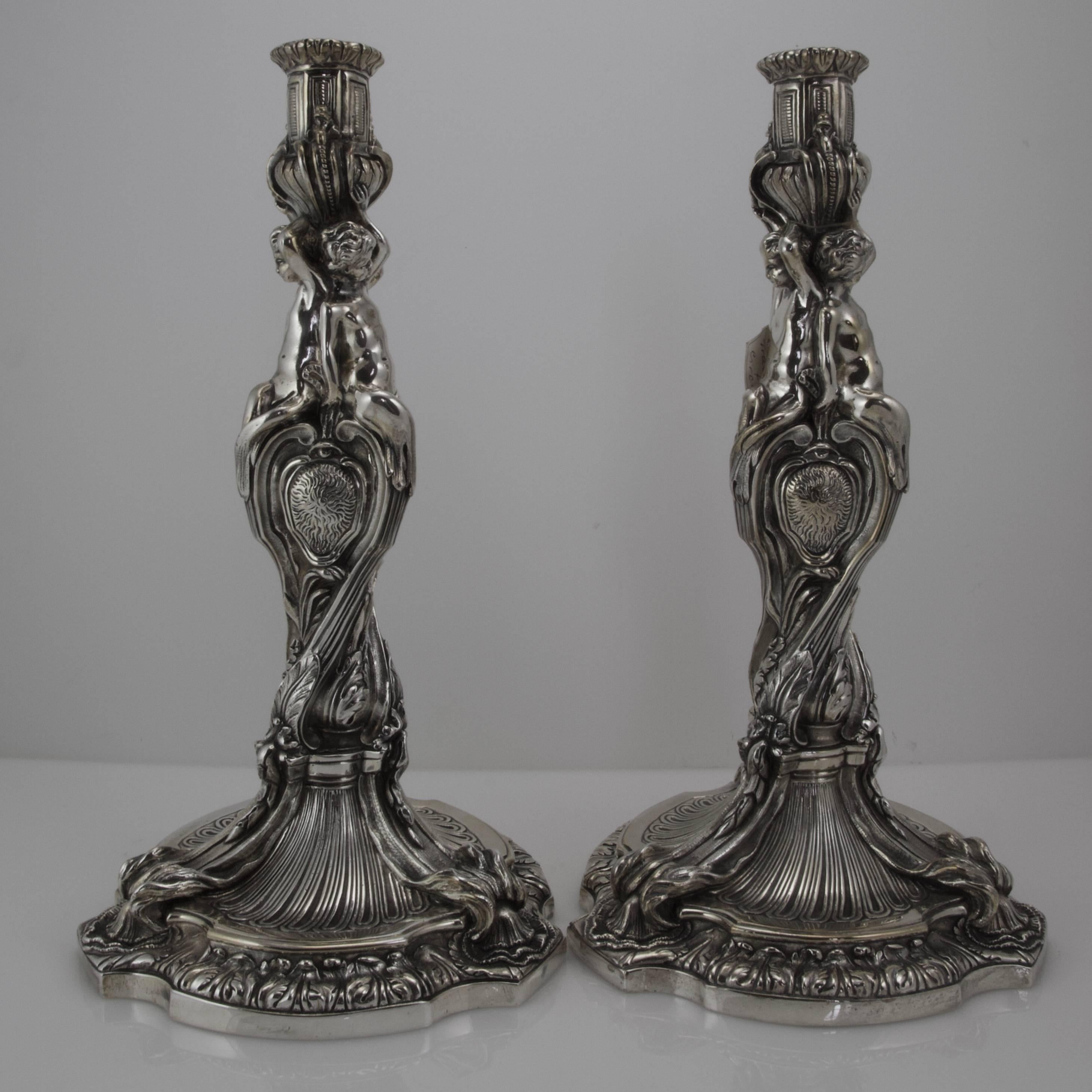 Tallness pair of candlesticks in bronze and silver plate showing all the decorative register of the Regency style. Baluster shaped form with swirling stem onto a shaped base. Three puttis as the atlantean supporting the lights. Three different