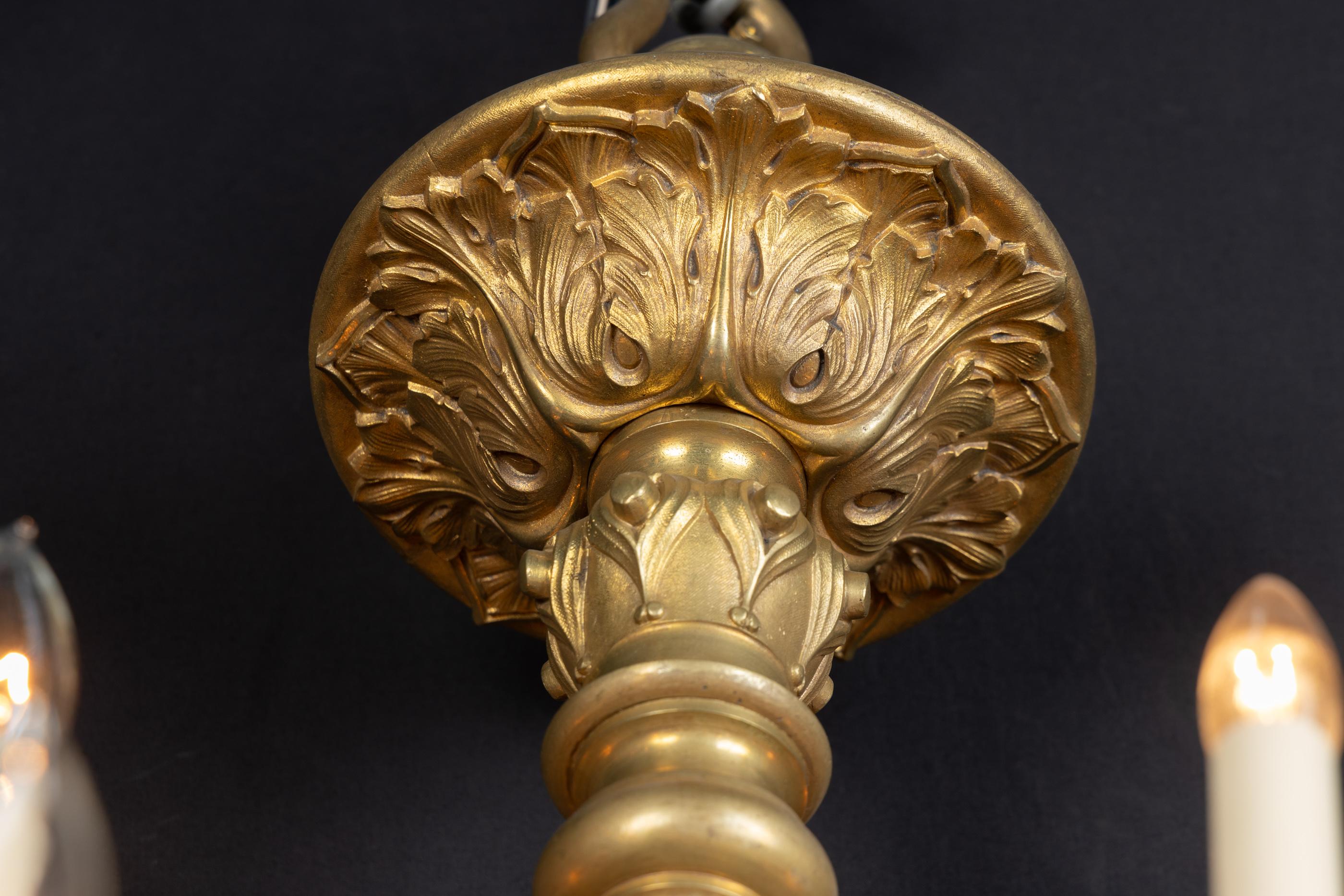 Esta pesada lámpara de araña Luis XIV del siglo XIX presenta dos niveles de bronce. Los elegantes candelabros de bronce, las bobeches y los brazos envueltos en acanto envuelven un centro adornado con más hojas de acanto, ligeras estrías y motivos.