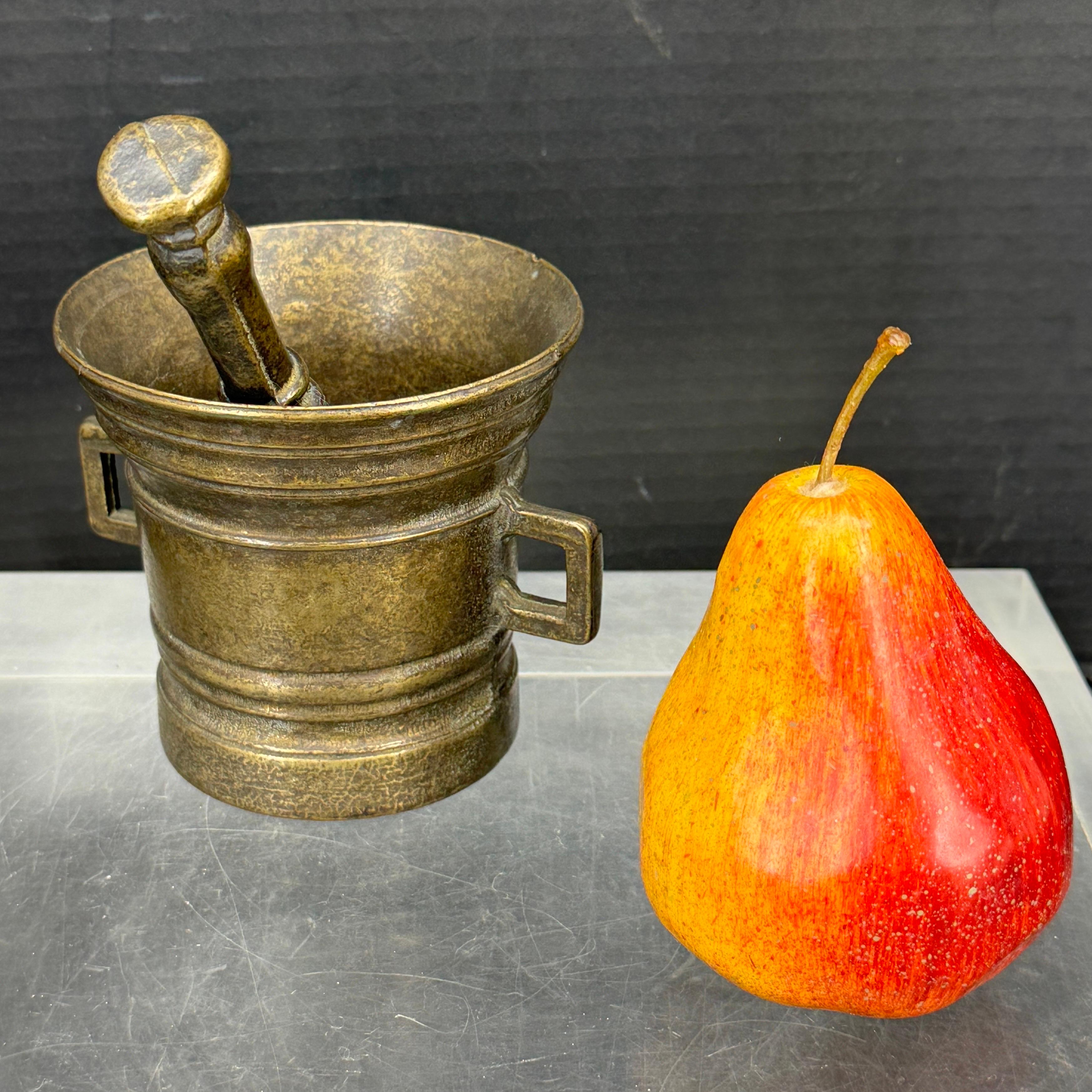 Un antico mortaio in bronzo con pestello originale dotato di due maniglie laterali e dettagli incisi. Questo set, trovato in Danimarca, sarebbe un'ottima aggiunta a una collezione esistente di questi popolari articoli di spezieria.
