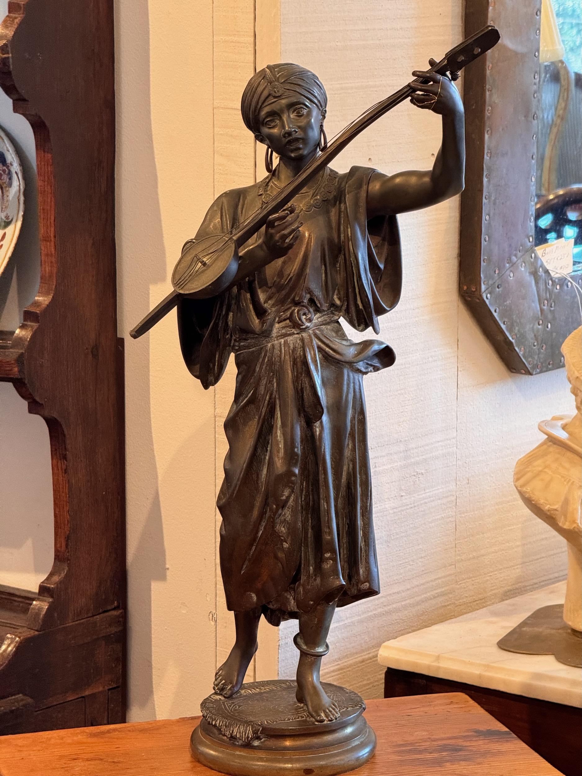 Una figura in bronzo di un musicista. An He sta suonando uno strumento a corda.