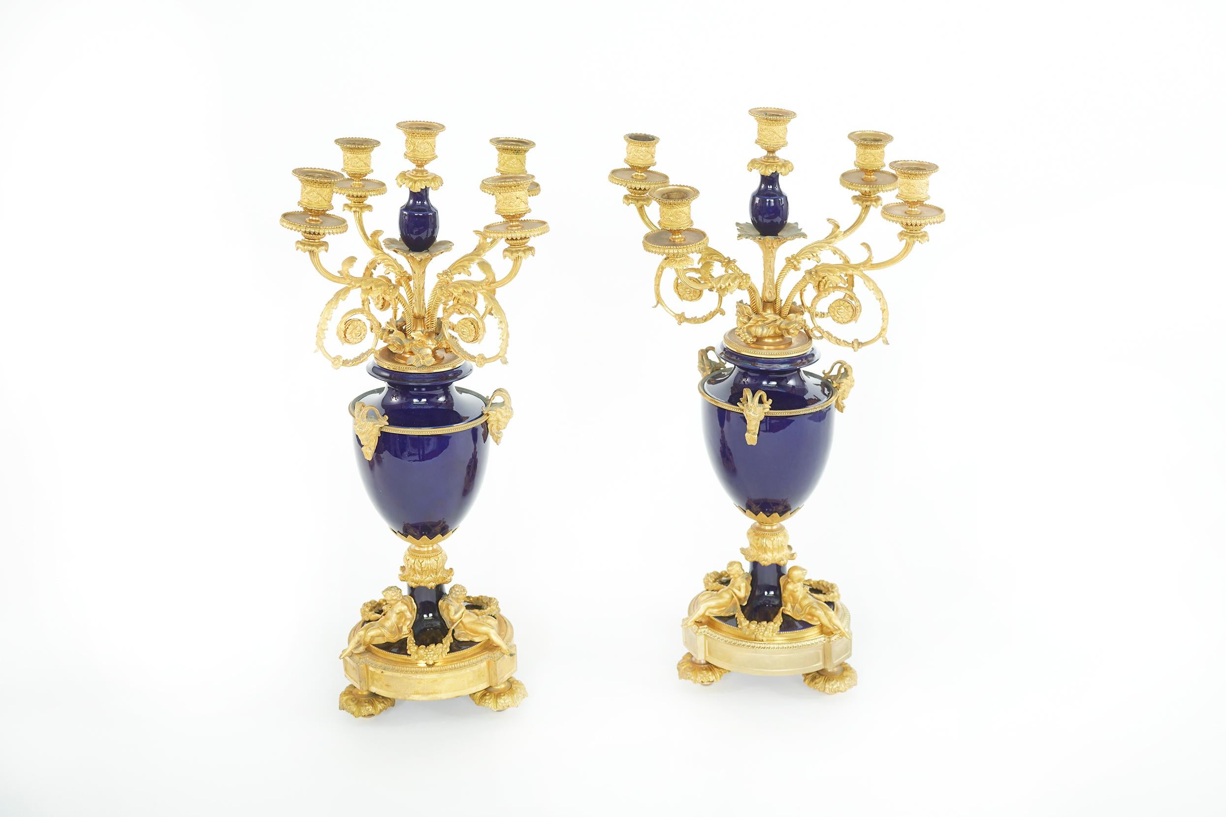 paire de candélabres à cinq lumières du XIXe siècle, montés en bronze doré et encadrés de porcelaine. Chaque pièce présente une forme d'urne avec des candélabres à cinq lumières sur un fond cobalt et des détails dorés. Chacun d'entre eux est en
