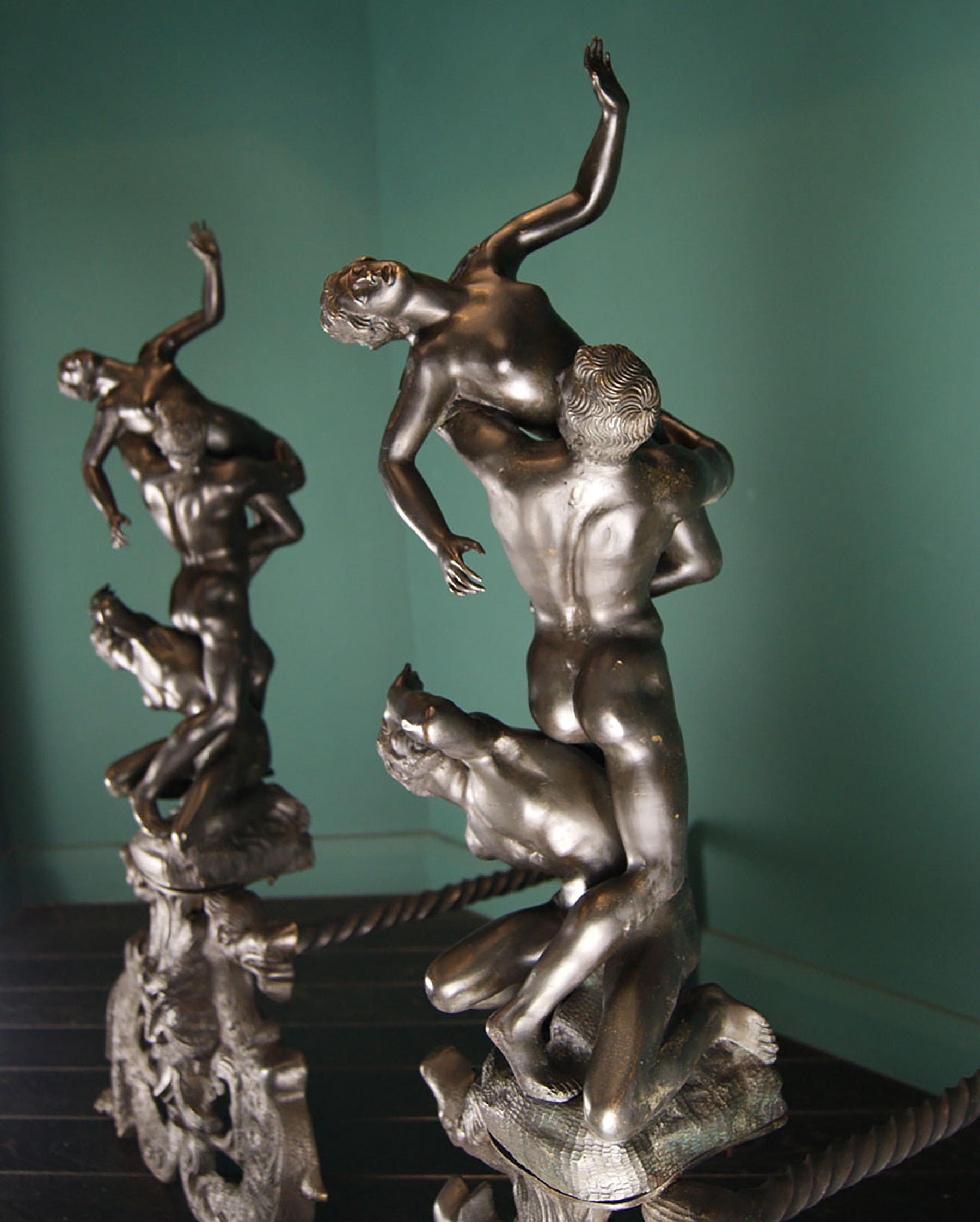 A beautiful large pair of nineteenth century bronze sculptural andirons of Giambologna's masterpiece 'Rape of the Sabine Women'. The base is formed from two ornate supporting dragons with a central mask. The log supports in wrought iron with twist