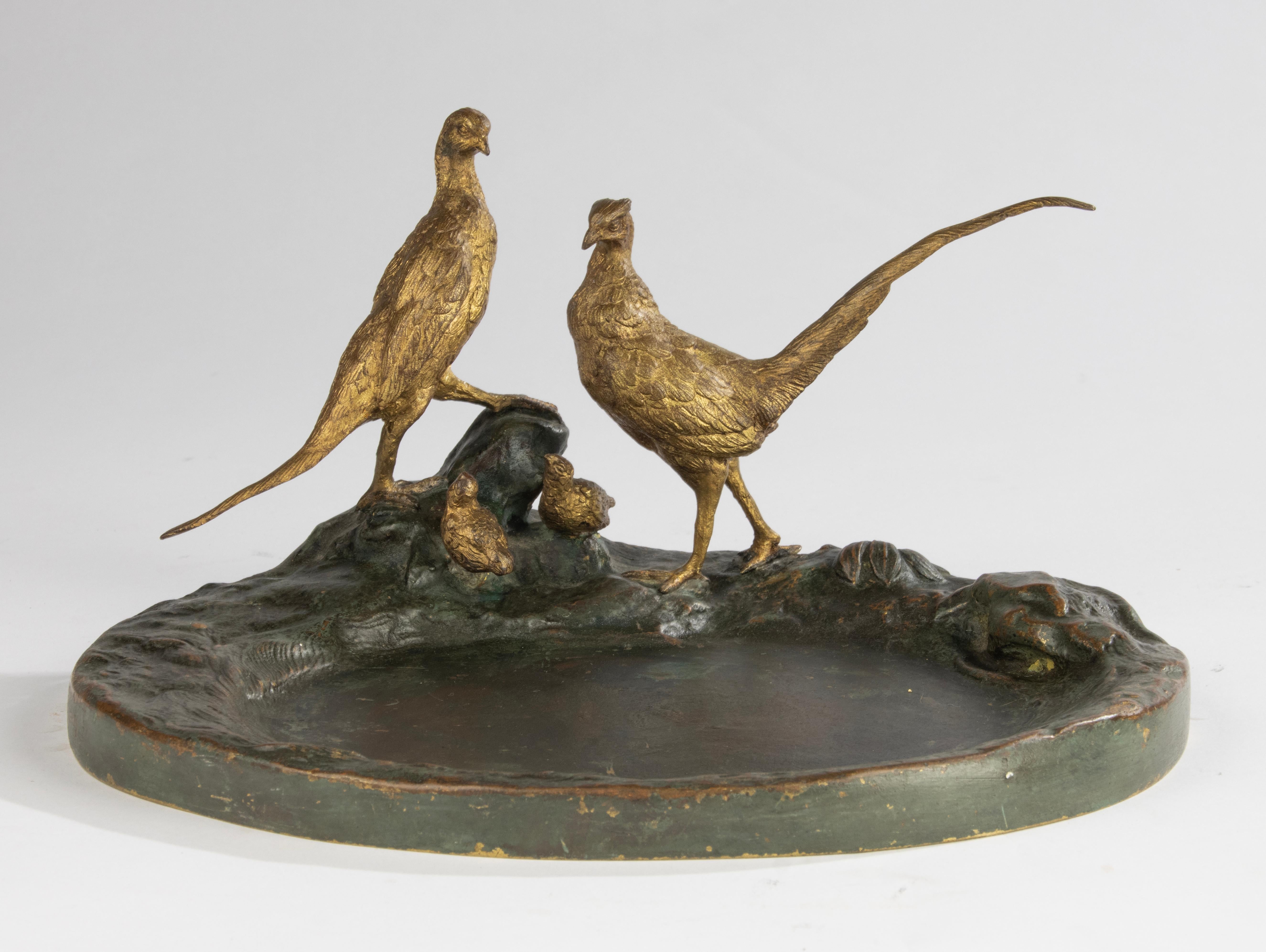 Una bellissima scultura in bronzo / vide poche, che cattura un sereno momento familiare nella natura, raffigurante una coppia di fagiani che vegliano attentamente sui loro pulcini. Il pezzo presenta dettagli raffinati e una patina calda che ne