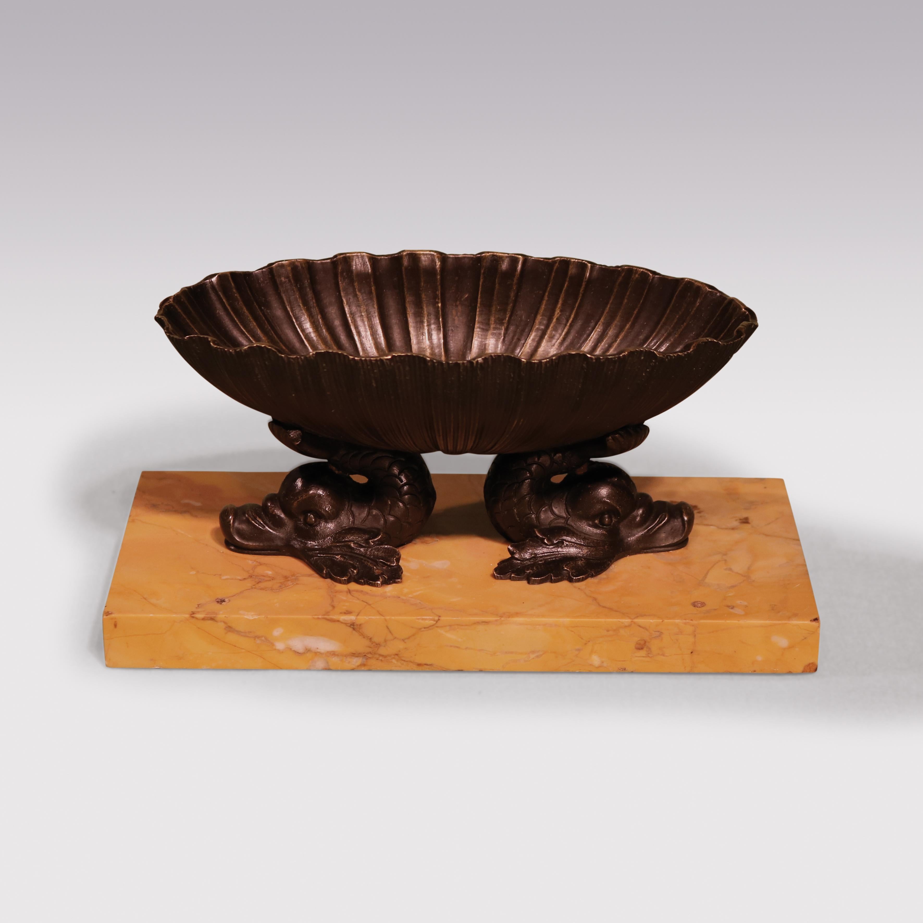 An early 19th century 'Grand Tour' bronze shell-shaped bath, supported on well-cast dolphins ending on Sienna marble base.