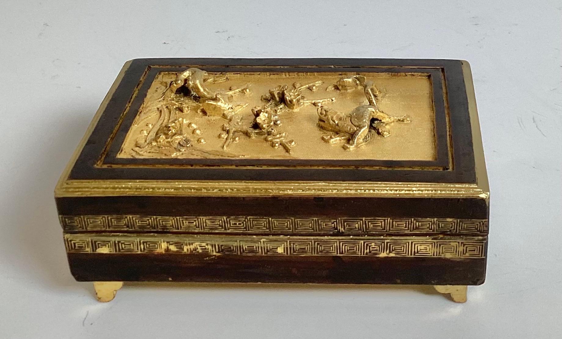 An Antique Chinese Gilt and patinated bronze tobacco box, late 19th Century.  The high relief gilt bronze work at the top with a patinated bronze outline.  The interior is gilt lined with the box resting on four small tapering feet. 