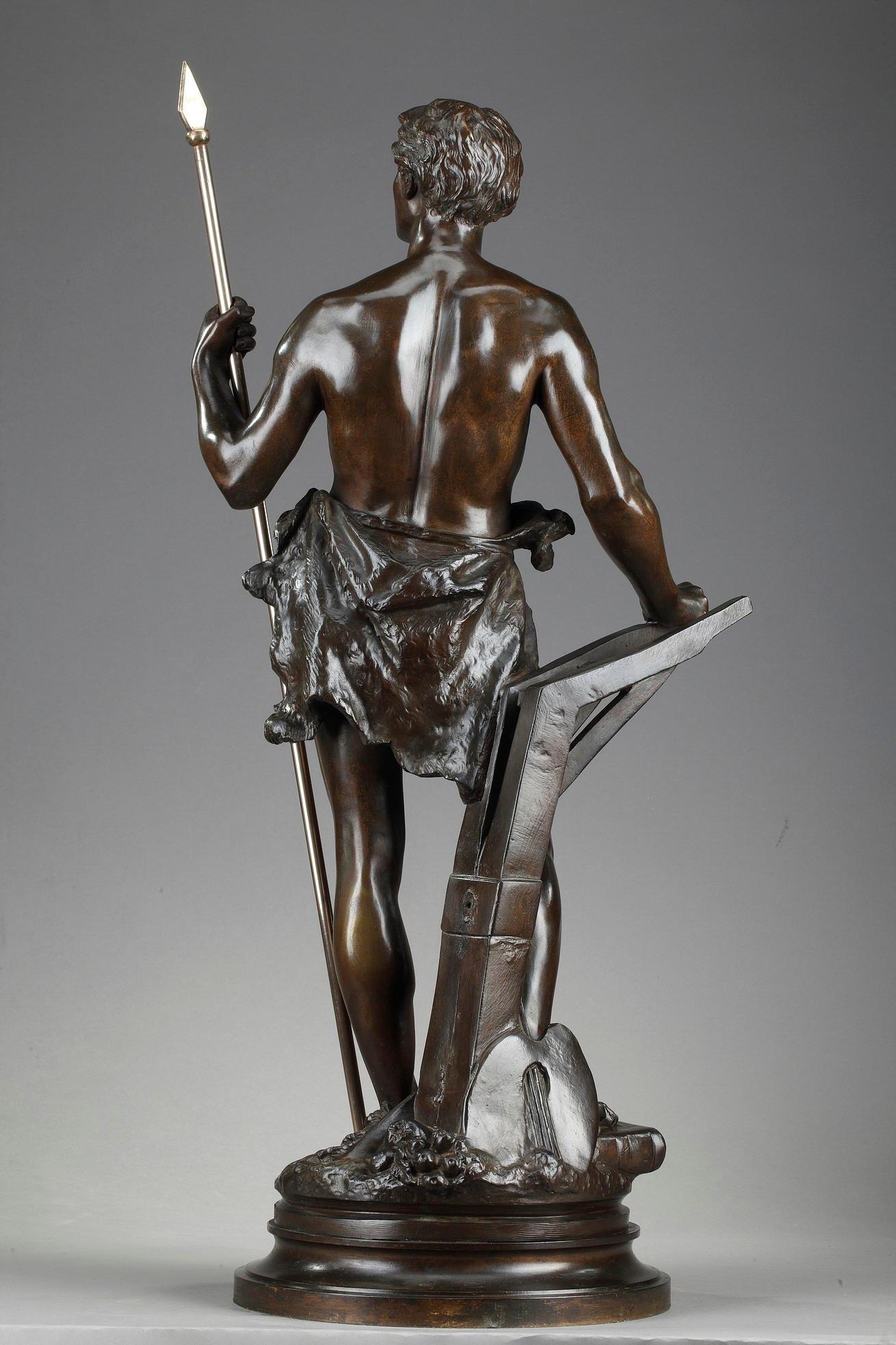Sculpture en bronze à patine brune d'Ernest Rancoulet représentant une allégorie du travail avec un jeune homme tenant une lance, qui symbolise le triomphe de la sagesse acquise par le travail et l'étude. À ses pieds, plusieurs objets font référence
