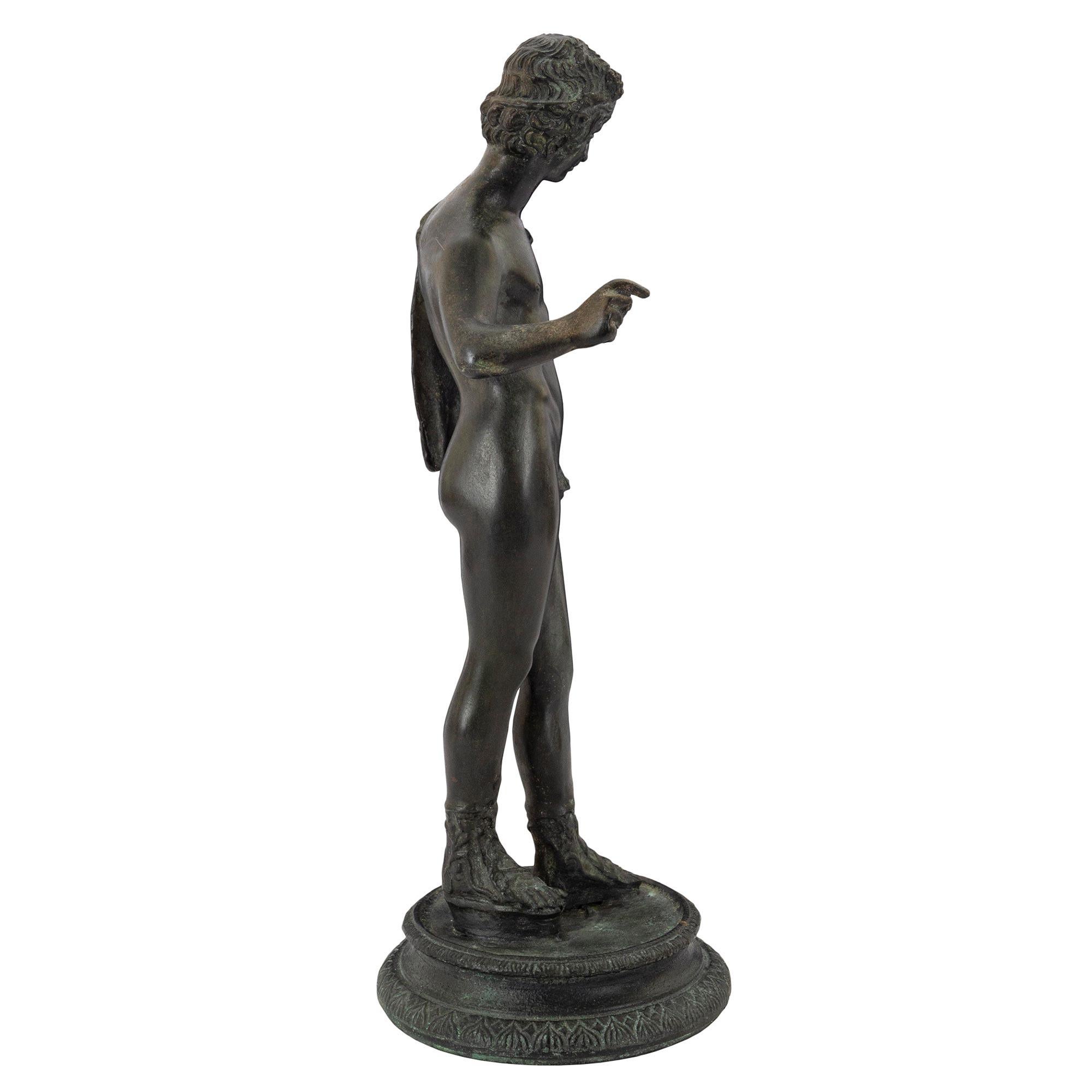 A handsome 19th century bronze statue of a young hunter. Raised on a circular moulded base with detailed chasing surrounds. The figure of a young male hunter with classic strapped sandals stands proudly wearing fabric draped on one shoulder