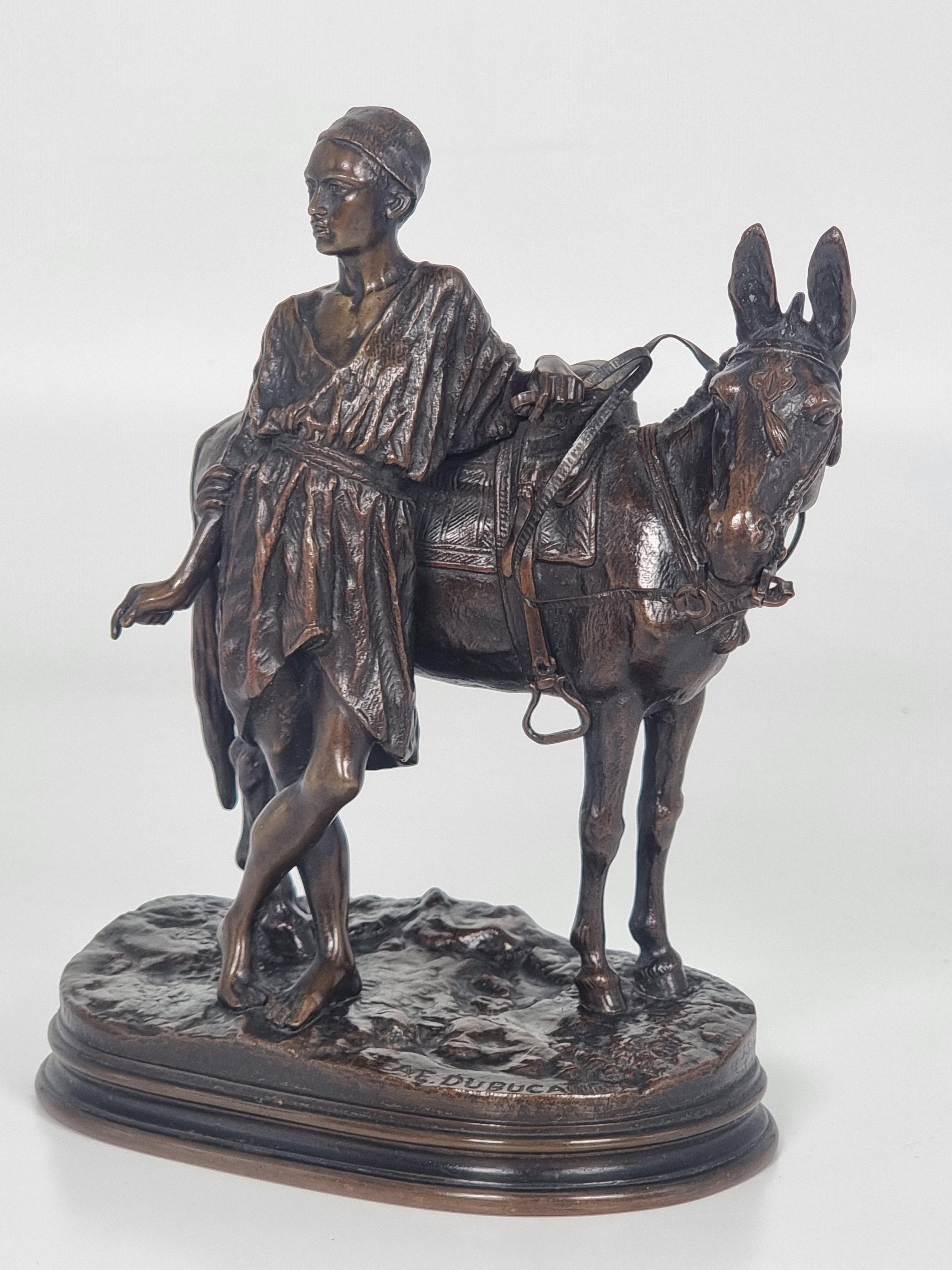 Questo studio in bronzo di eccezionale qualità è opera del maestro scultore Alfred Dubucand (1828 - 1924).  Raffigura un giovane egiziano semplicemente in piedi accanto al suo mulo, che indossa una sella elaborata, staffe e briglie, e il giovane