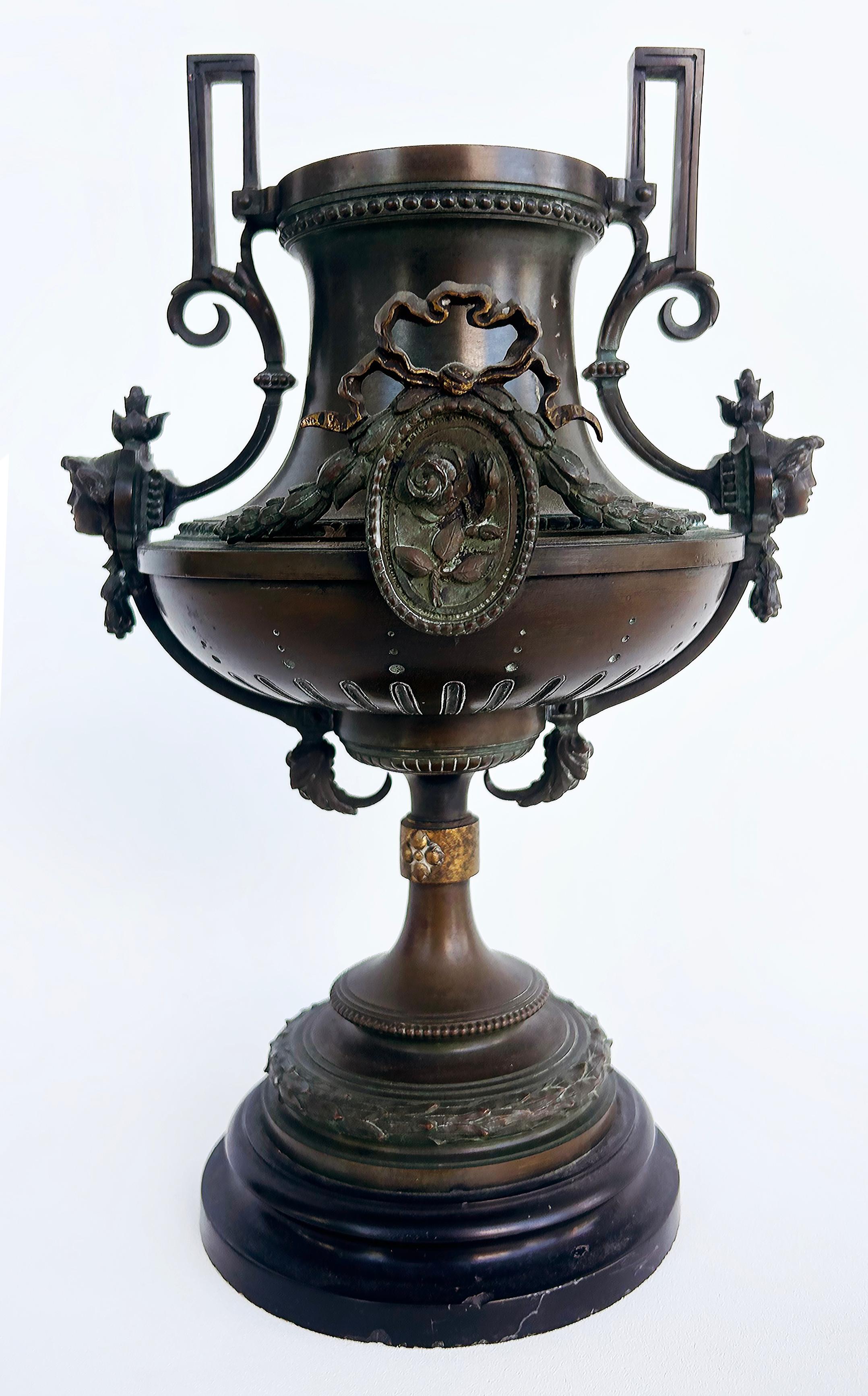 19th-Century Bronze Urns with Gilt Cartouches on Stone Bases, Pair

Offered for sale is a pair of  late 19th-century bronze urns with gilt decorations.  This ornate pair of urns is decorated with oval beaded cartouches with floral motifs and