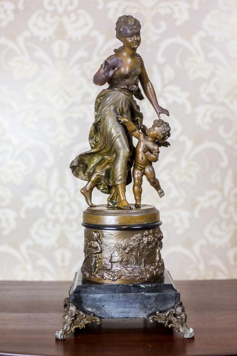 This figurine, dated fourth quarter of the 19th century, depicts a young girl playing with a putto.
It is made of bronzed zamak and signed by Hippolyte Moreau.
The figures are placed on a base covered with genre scenes and a square stone base with