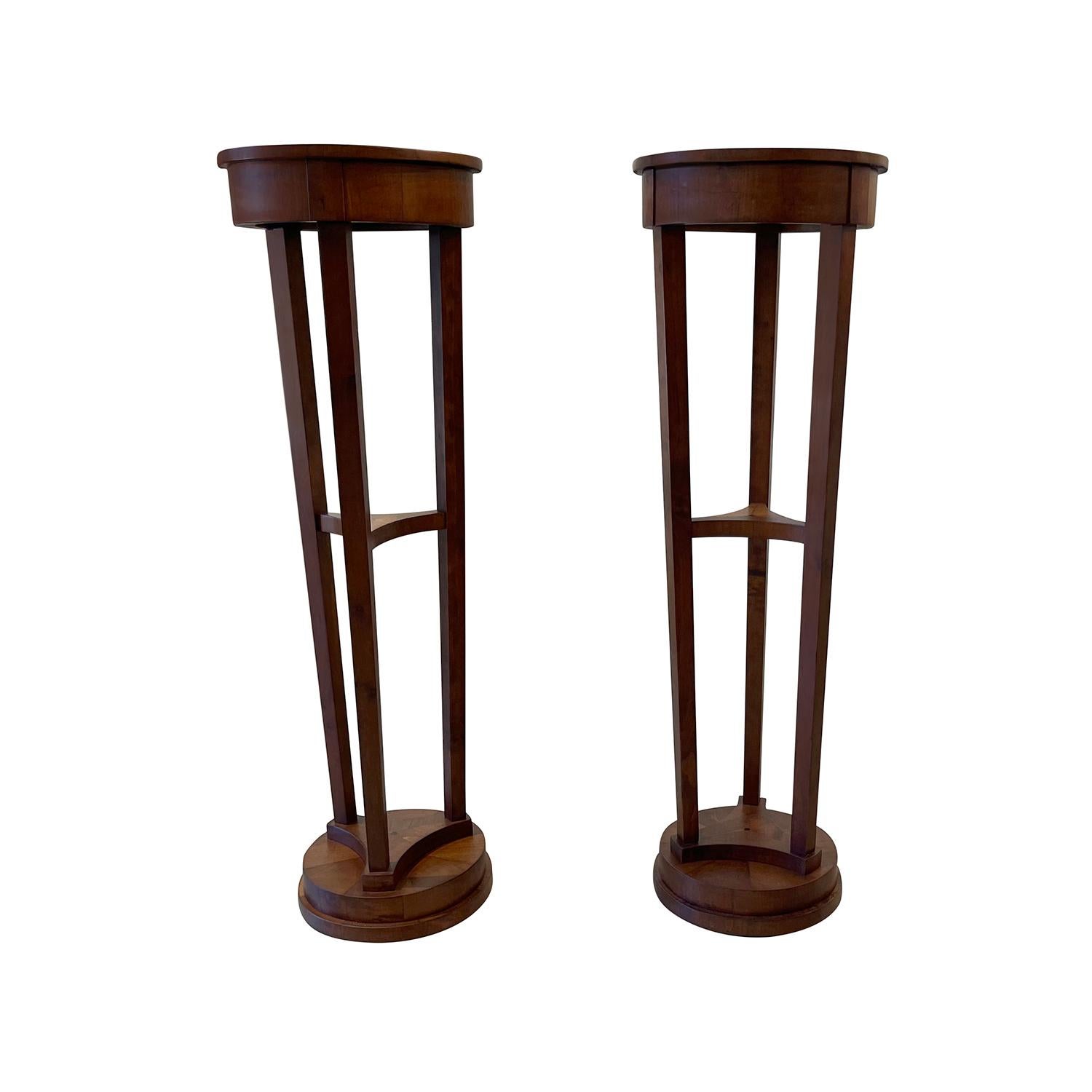 An antique French pair of pedestals-torchers made of hand crafted Mahogany, in good condition. Each of the detailed Parisian shellac polished podiums are composed with a small centre shelf, enhanced by detailed wood carvings. The living room décor