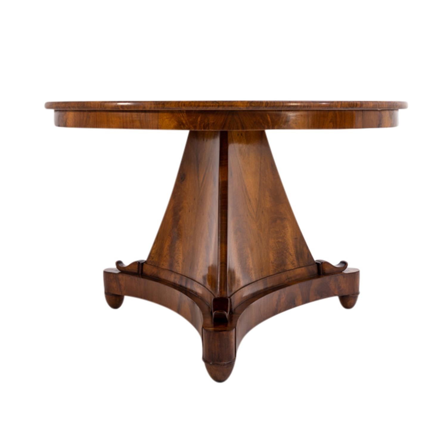 A round, antique early German Biedermeier center table made of hand crafted shellac polished Walnut, in good condition. The top of the detailed dining table is foldable, particularized by a star-shaped veneer pattern. The small table is supported by