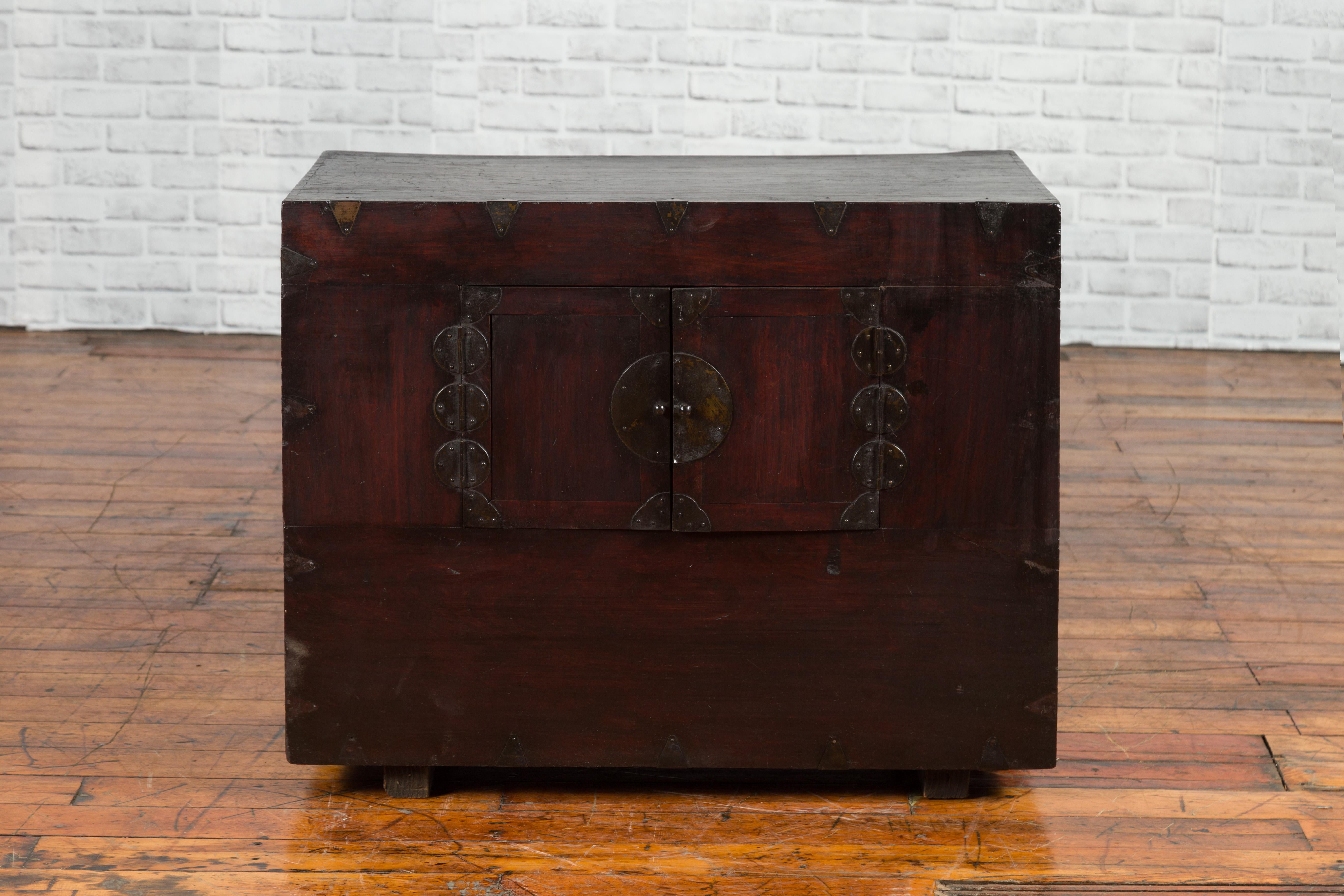 A Korean small cabinet from the 19th century, with brass hardware and brown lacquer. Created in Korea during the 19th century, this brown lacquered small cabinet features a linear shape perfectly accented with dark patinated brass hardware. Two