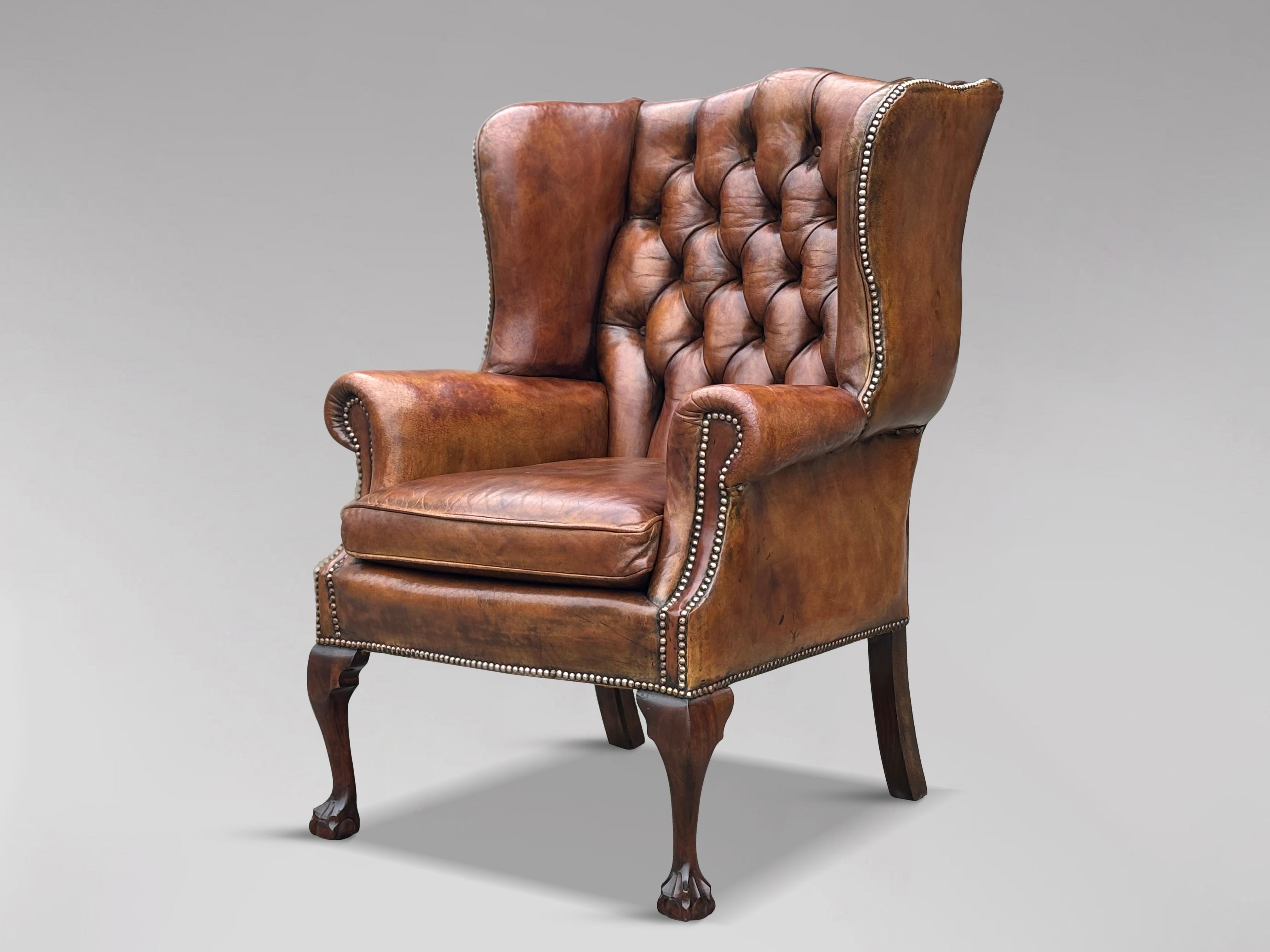 Poltrona ad ala con schienale a bottoni in pelle marrone del XIX secolo, di alta qualità e intatta, in stile George III. La struttura sostanziale e ben sagomata presenta uno schienale e dei braccioli imbottiti con bottoni profondi, tutti rivestiti