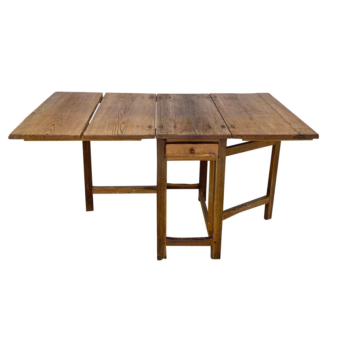 An antique Swedish Gustavian farmhouse table made of hand crafted Walnut with one drawer, in good condition. The Scandinavian rustic kitchen table is composed with two drop-leaves, the hinges are made of hand crafted wrought iron, supported by a