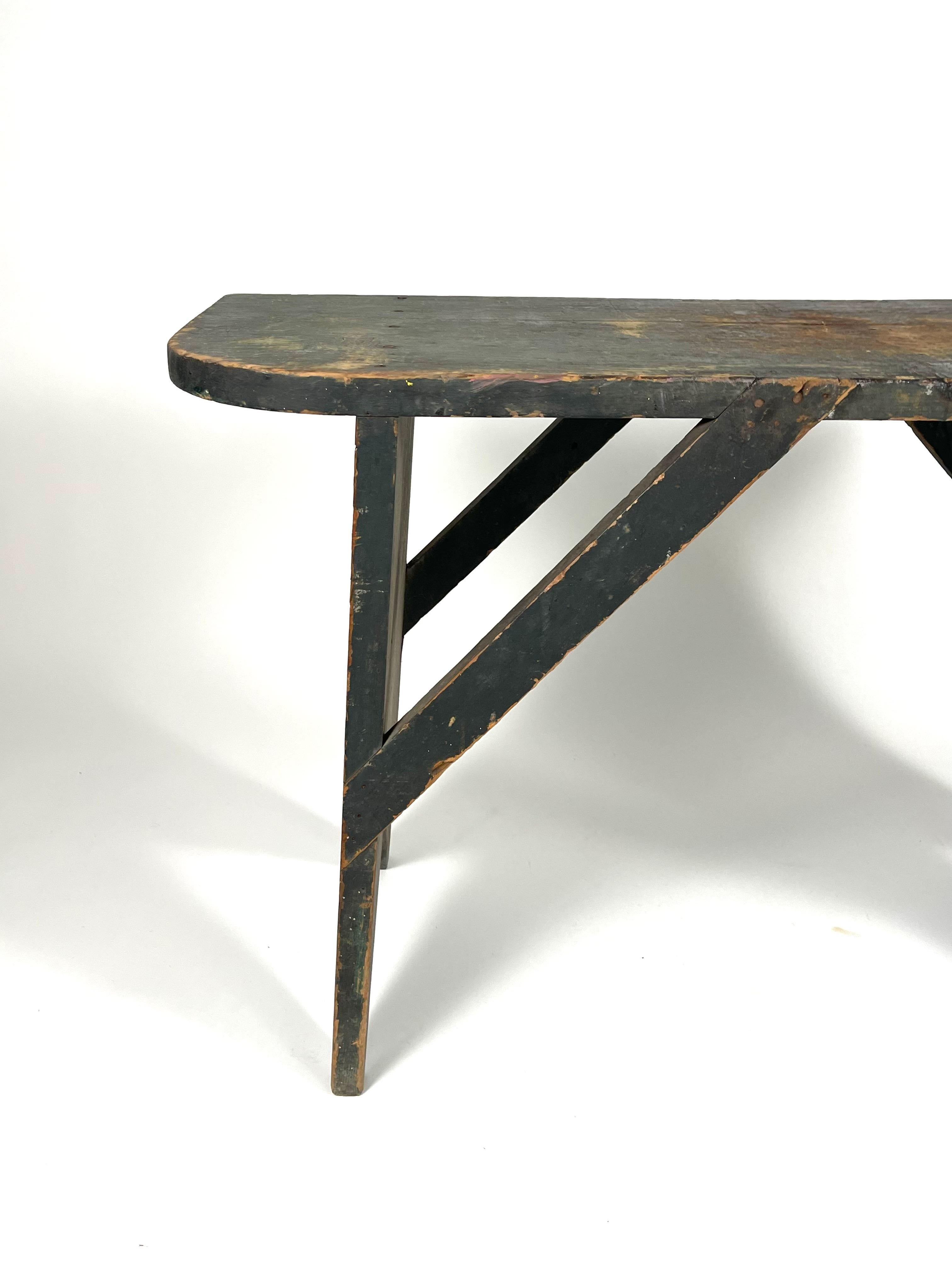 A 19th century bucket bench in old green paint of rectangular form with curved ends, the sawtooth cut plank legs joined by diagonal cross stretchers. Wonderful graphic form and useful both as a bench or a table.
Historically, a bucket bench was