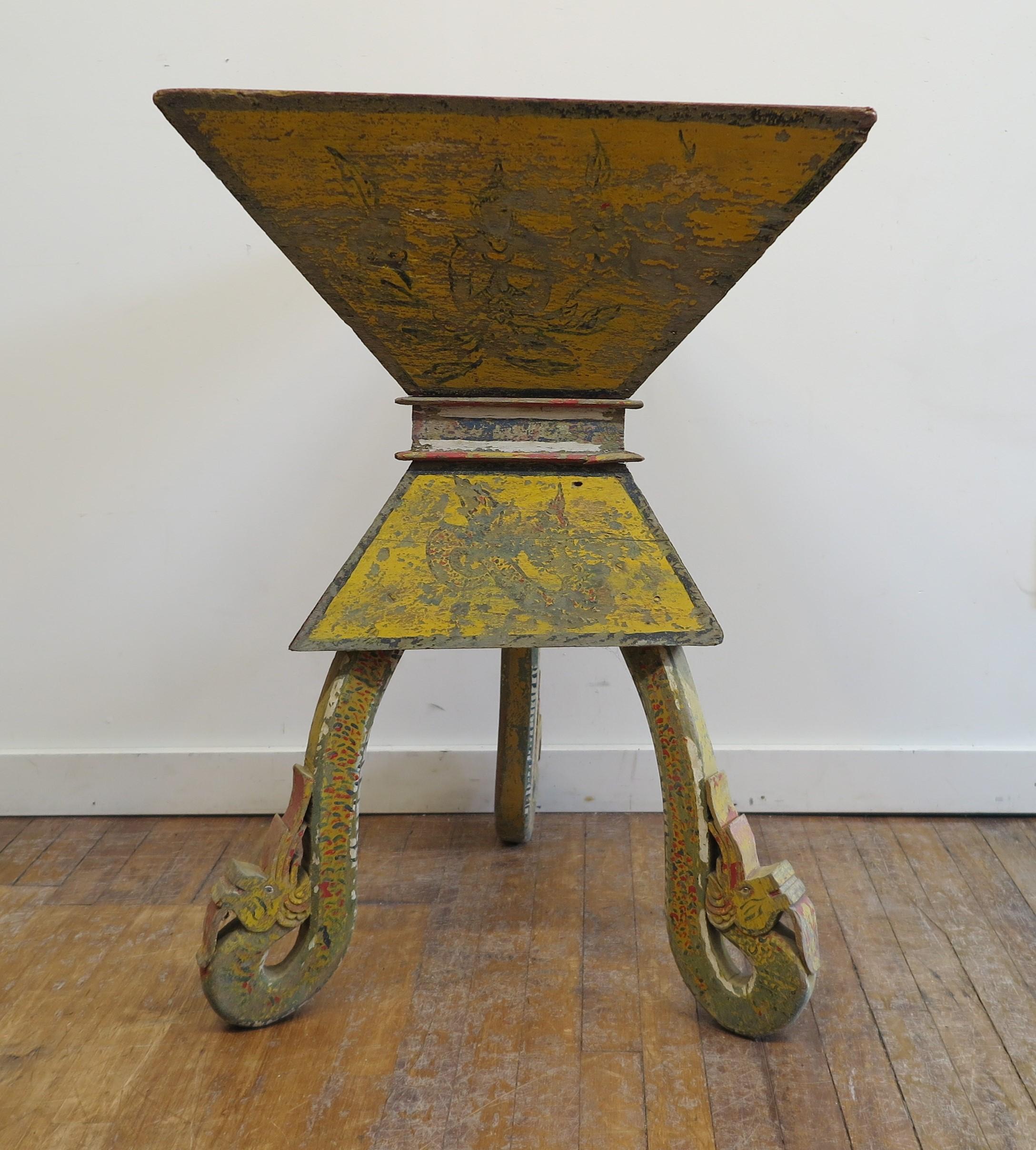 This stunning rustic Buddha box stand table is a late 19th century offering box. Significant Triangular shape box stand table set on legs carved as Naga's and painted. Naga's are often represented as door guardians. In more remote villages open