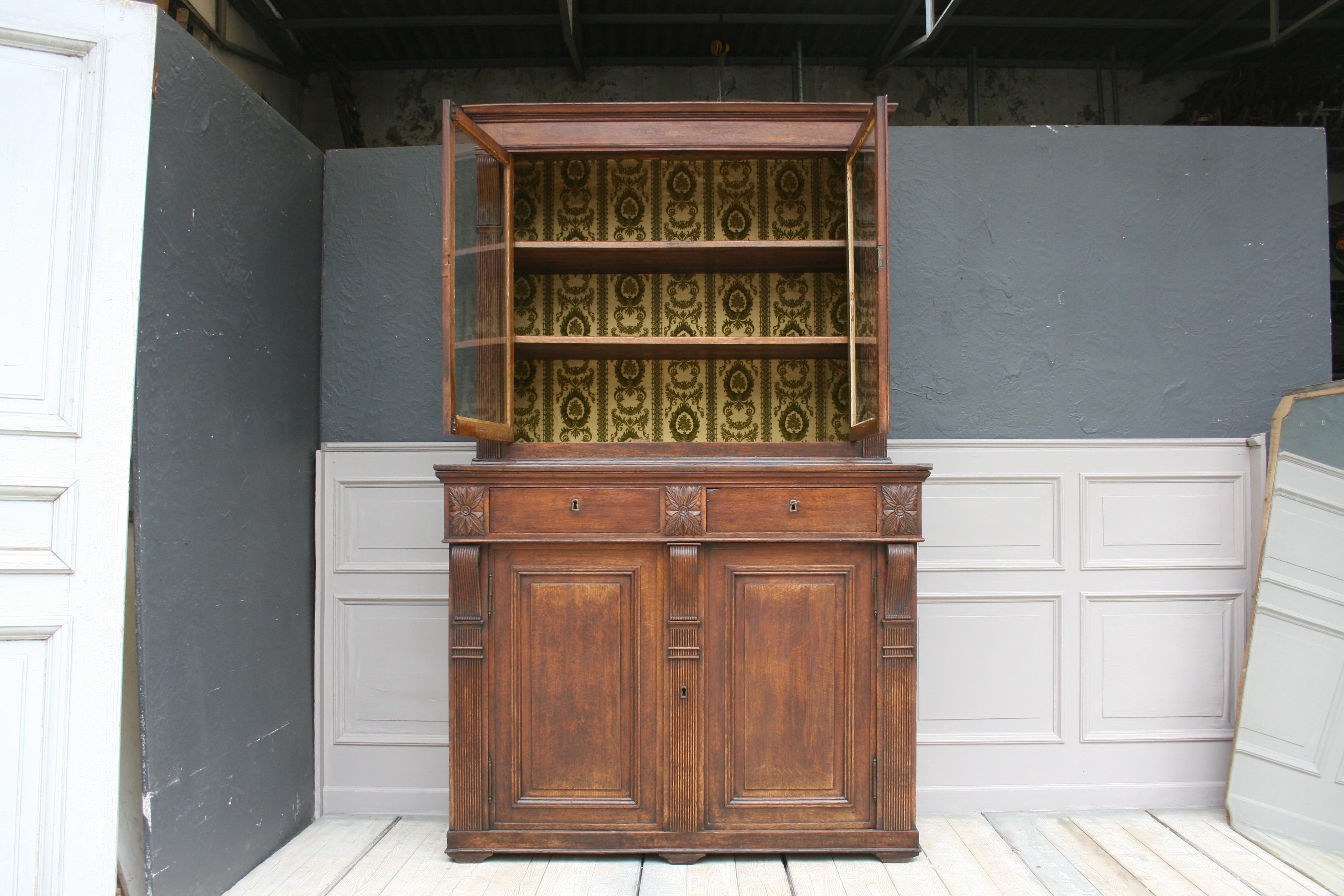 Original antique buffet cabinet from circa 1860. The cabinet is made of oakwood and has 2 doors in the lower part with a shelf behind it, as well as 2 drawers in the middle part and 2 glass doors with the beautiful original antique hand blown glass