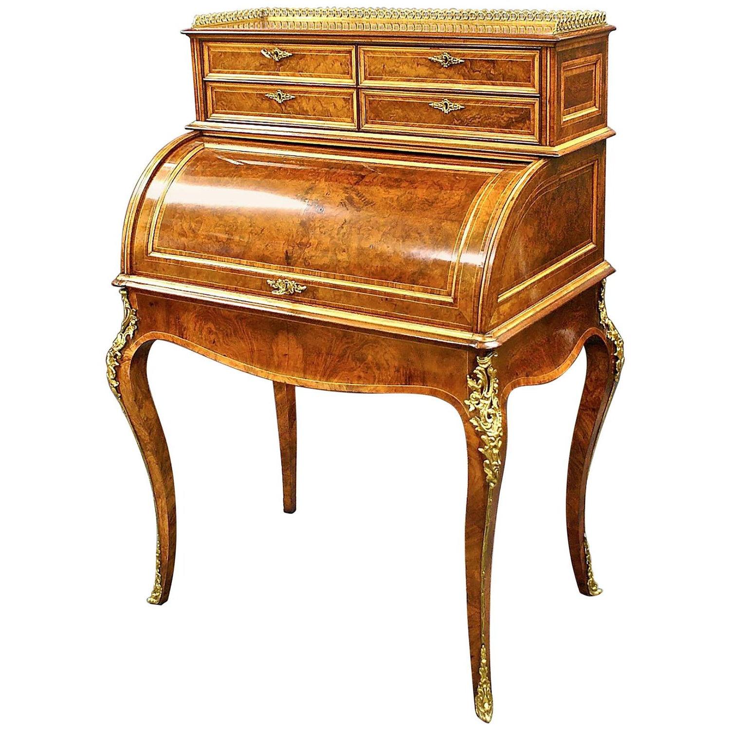 This stunning and excellent quality English burr walnut cylinder bureau features an ornate Ormolu trim, pierced gallery and shaped apron that is supported on cabriole legs. The bureau has tulip wood banding and boxwood detailing. The interior