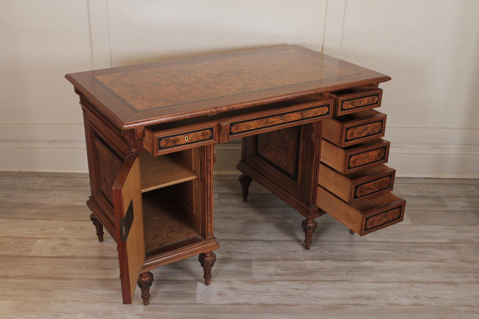 Burled walnut Renaissance revival desk. The highly figurative burled walnut top with ebonized accents on the top, drawers and feet.
Two upper drawers flanked by one set of drawers and a shelved compartment on the other. Diminutive size dimensions: