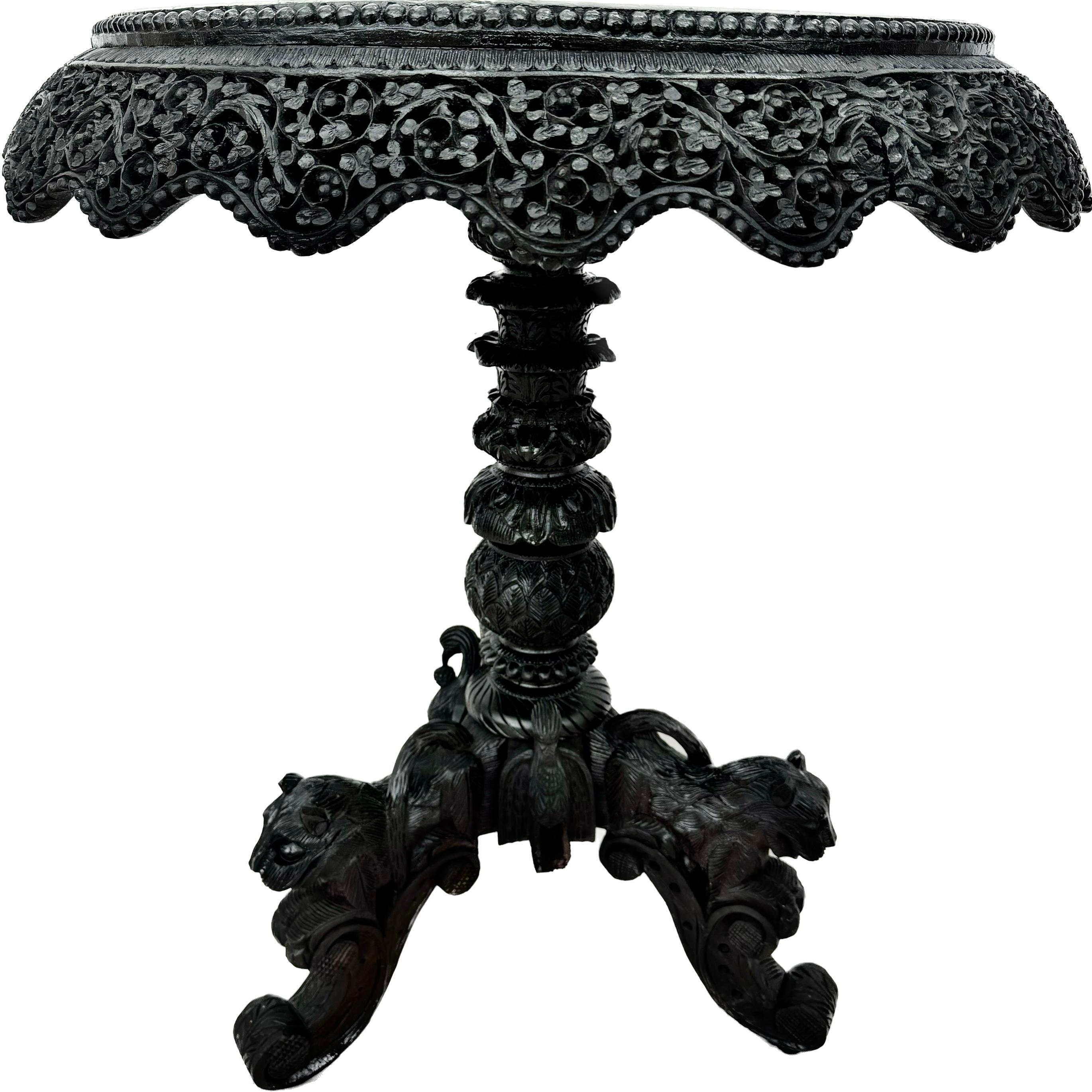 Exquise table d'appoint ronde anglo-indienne birmane sculptée du 19e siècle. La table est dotée d'un tablier filigrané et sculpté de façon complexe et d'une base sur piédestal. La base est ornée de têtes de tigre sculptées sur des pieds tripodes. 