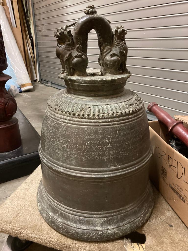 19th century Burmese bronze temple bell with original carved hard wood stand, painted iron hanging bracket, and striker. This rare cast bronze bell has a splendid sculptural and spiritual presence. 

The bell has a long inscription on the upper