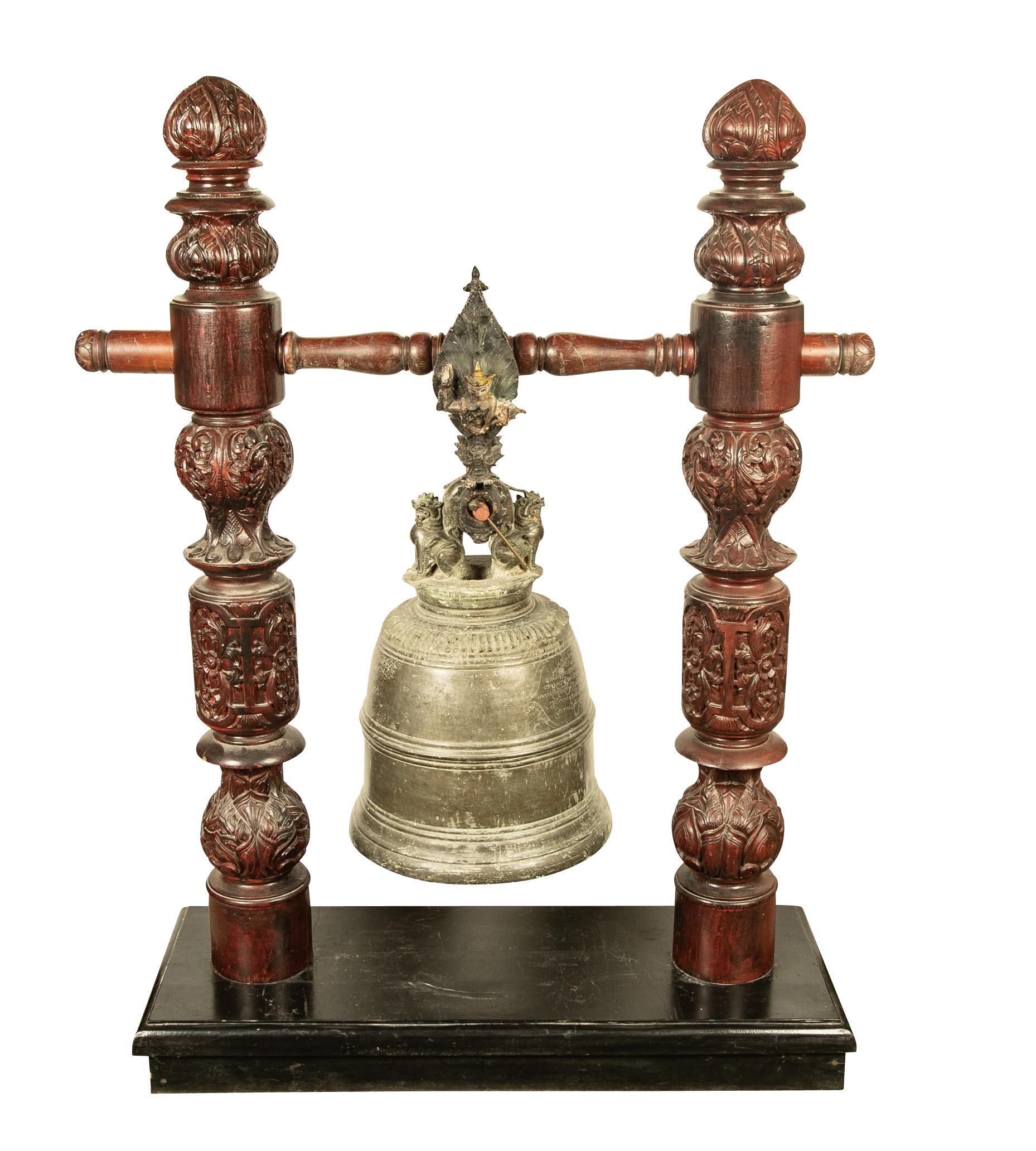 19th century Burmese bronze temple bell with original carved hardwood stand, painted iron hanging bracket, and striker. This rare large scale cast bronze bell has a splendid sculptural and spiritual presence. 

The bell has a long inscription on the