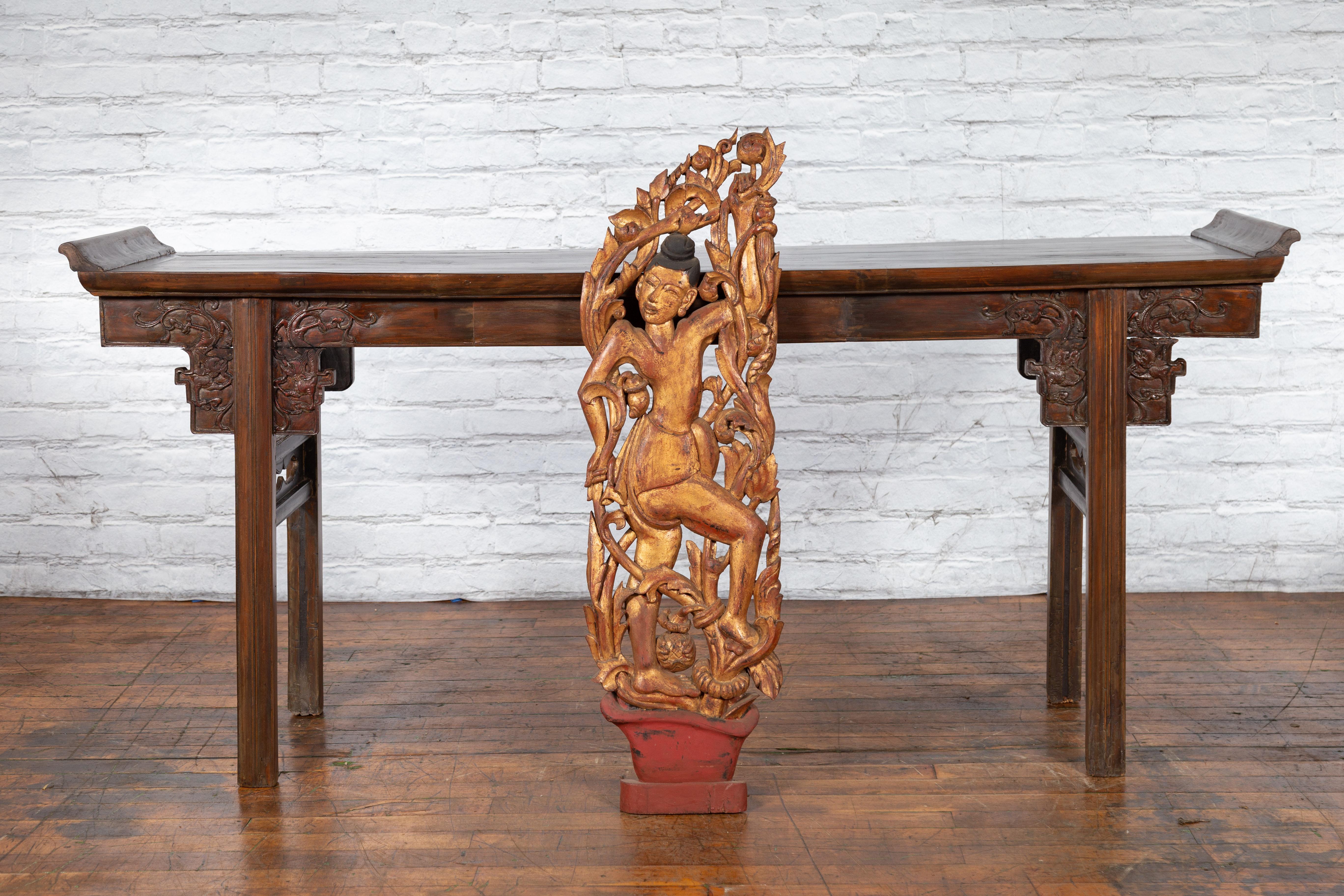 An antique Burmese giltwood sculpture from the 19th century, depicting a dancer with carved foliage. Created in Burma during the 19th century, this giltwood carving attracts our attention with its lively depiction of a dancer surrounded by foliage.