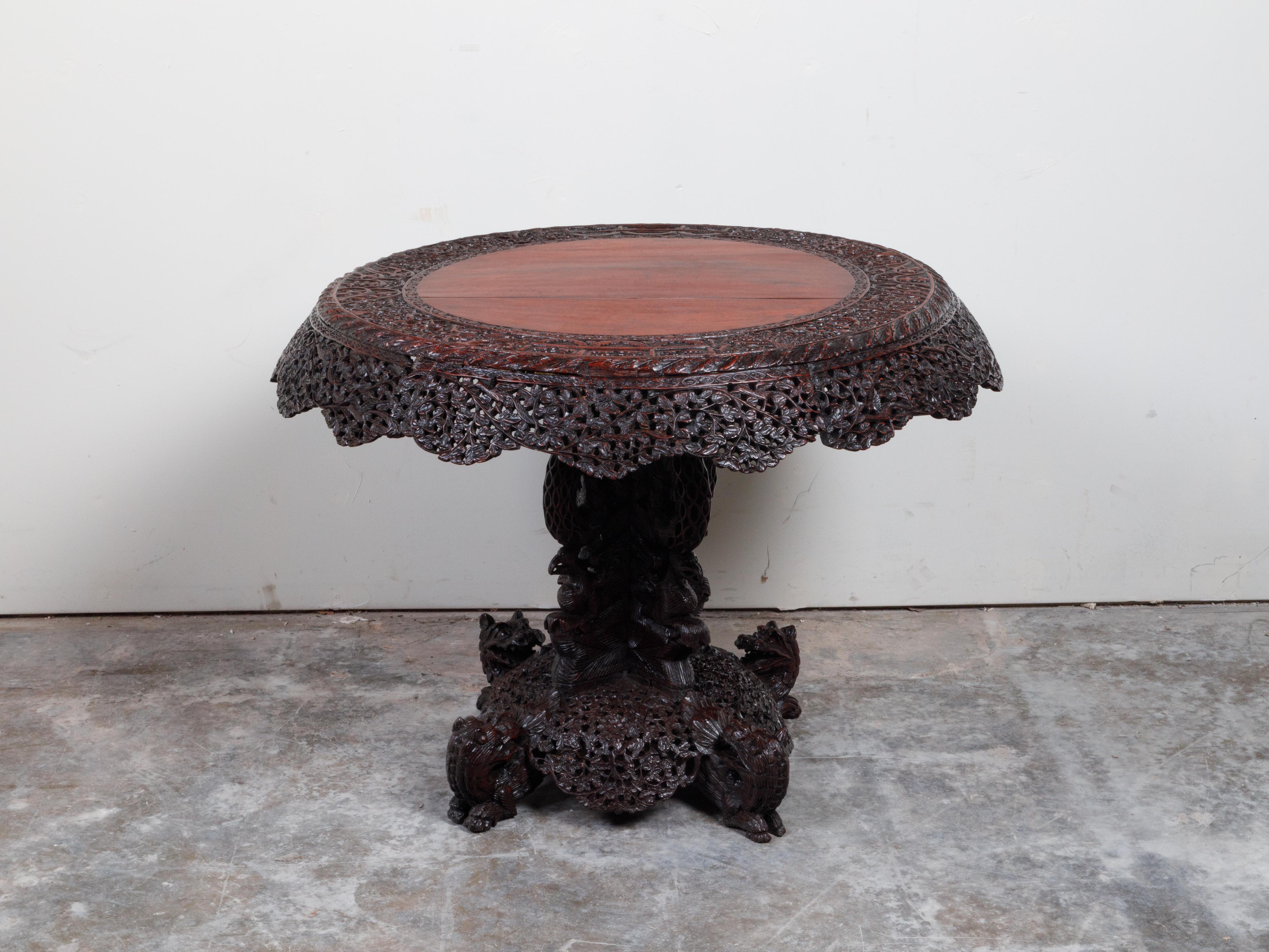 A Burmese hand-carved side table from the 19th century, with mythical animals and foliage. Created in Burma during the 19th century, this side table captures our attention with its two-toned appearance and beautifully carved apron. Raised on a