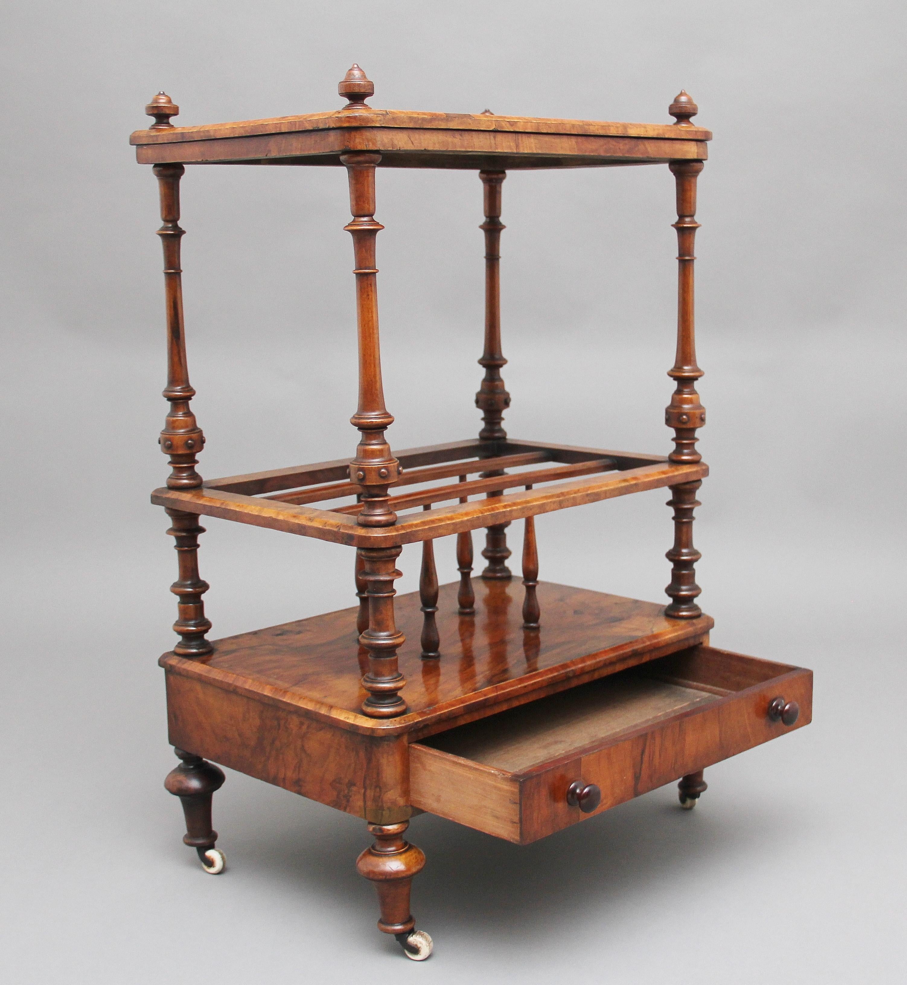 19th century burr walnut Canterbury, the burr walnut top having floral inlay decoration and turned finials in each corner, supported on finely turned columns, the middle section having three divisions which are divided with turned spindles, with a