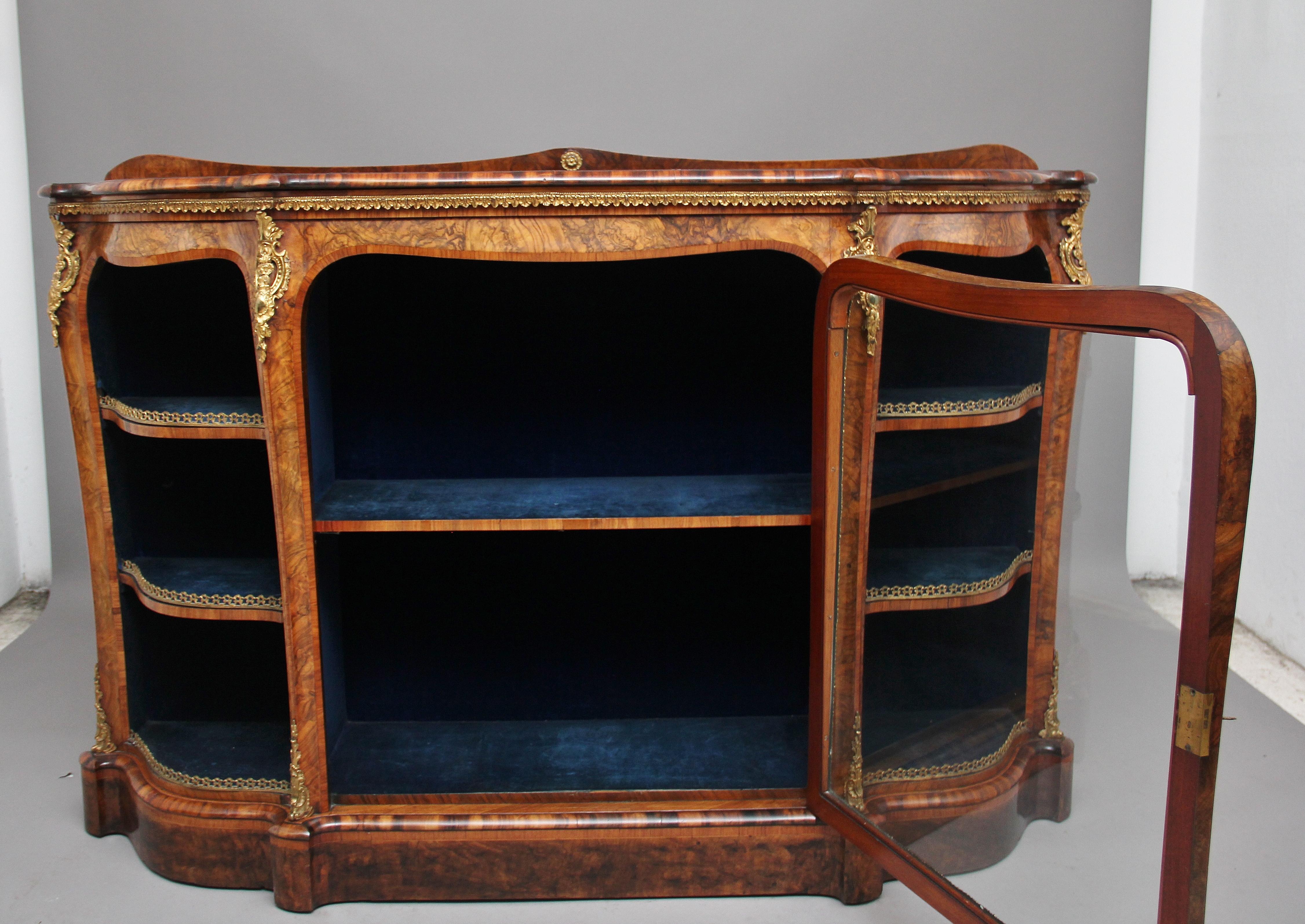 A fabulous quality 19th century burr walnut credenza, the shaped moulded top with satinwood crossbanding, above a gilt metal stiff leaf frieze and a central glazed and shaped cabinet door with conforming crossbanding, enclosing a velour lined