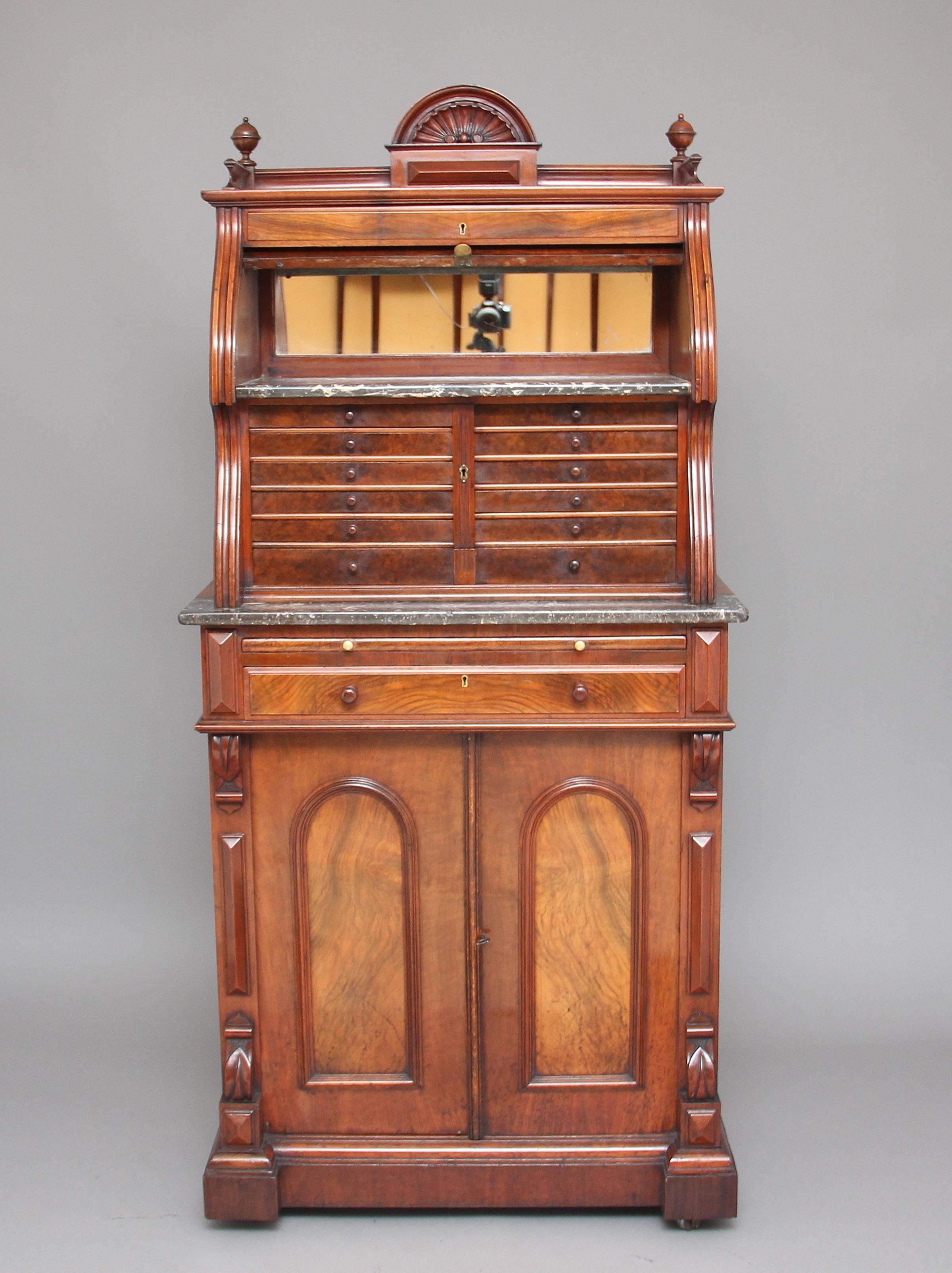 19th century burr walnut dentist cabinet, the top section having a carved shell top gallery with decorative finials either side the cylinder opening to reveal a mirror and grey variegated and speckled marble, twelve graduated burr walnut drawers