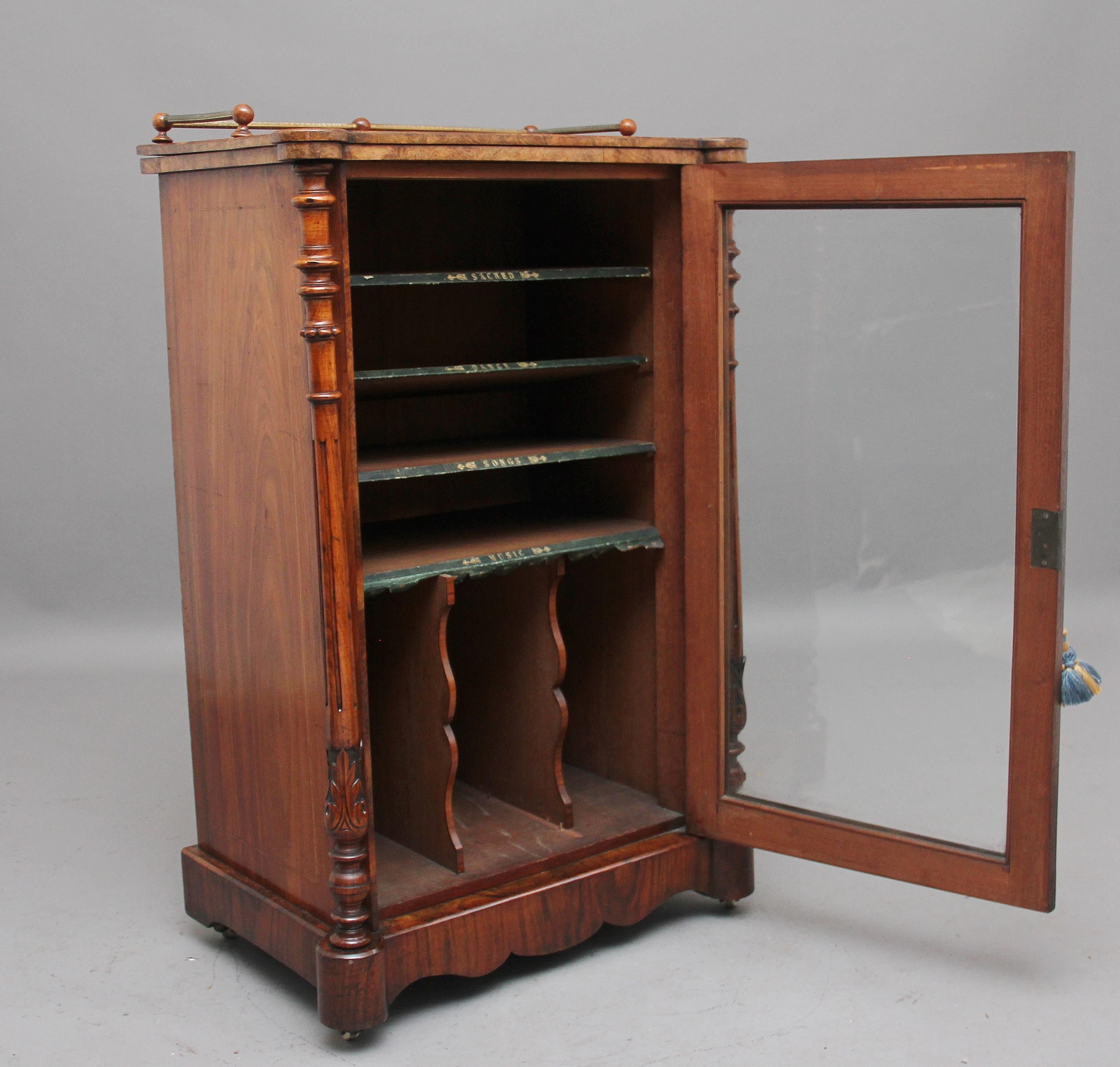 19th century burr walnut inlaid music cabinet, the wonderfully figured and shaped top having a floral inlay at the centre, decorated with a engraved turned rail, having a single glazed door below enclosing four shelves and two dividers at the