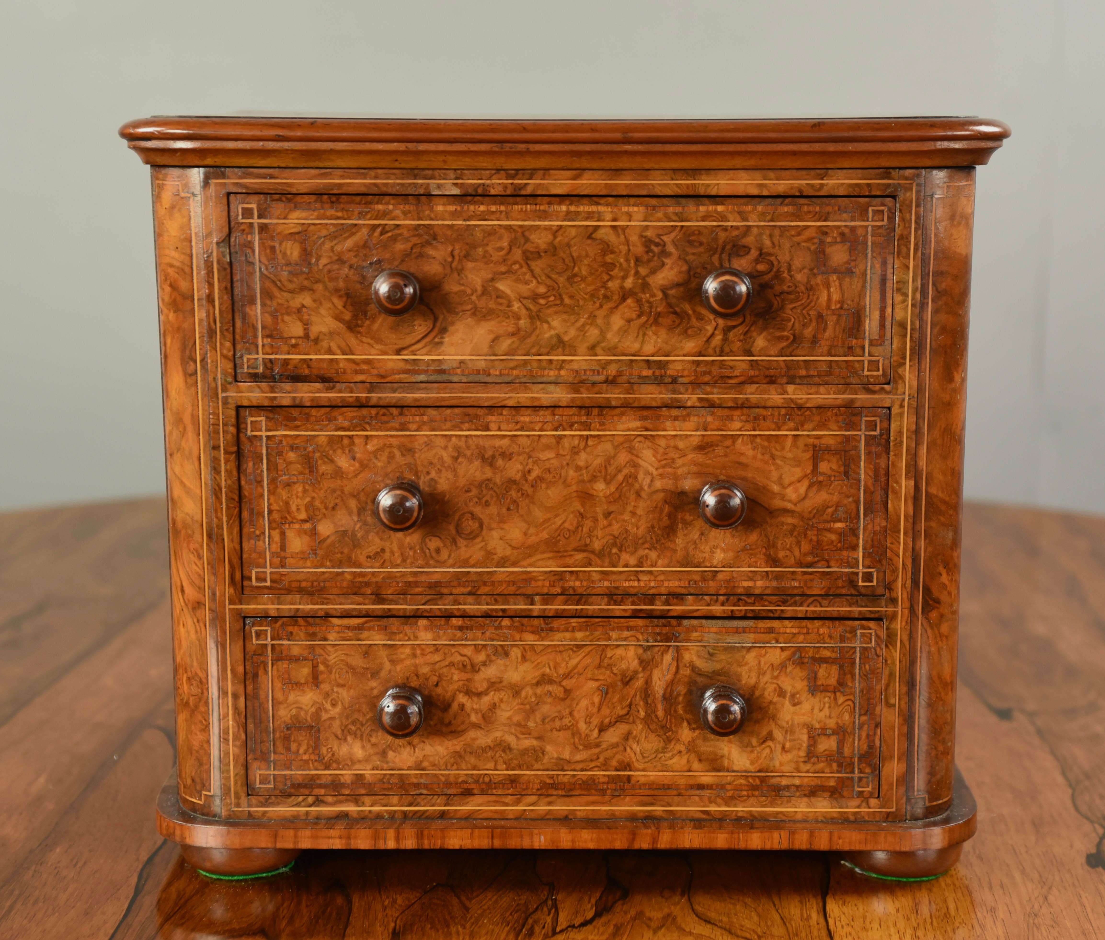 Fine quality mid 19th Century Victorian antique burr walnut table top chest of drawers that has three graduating mahogany lined drawers with fine turned walnut knob handles. It stands on bun feet. This is a very unusual small chest of good