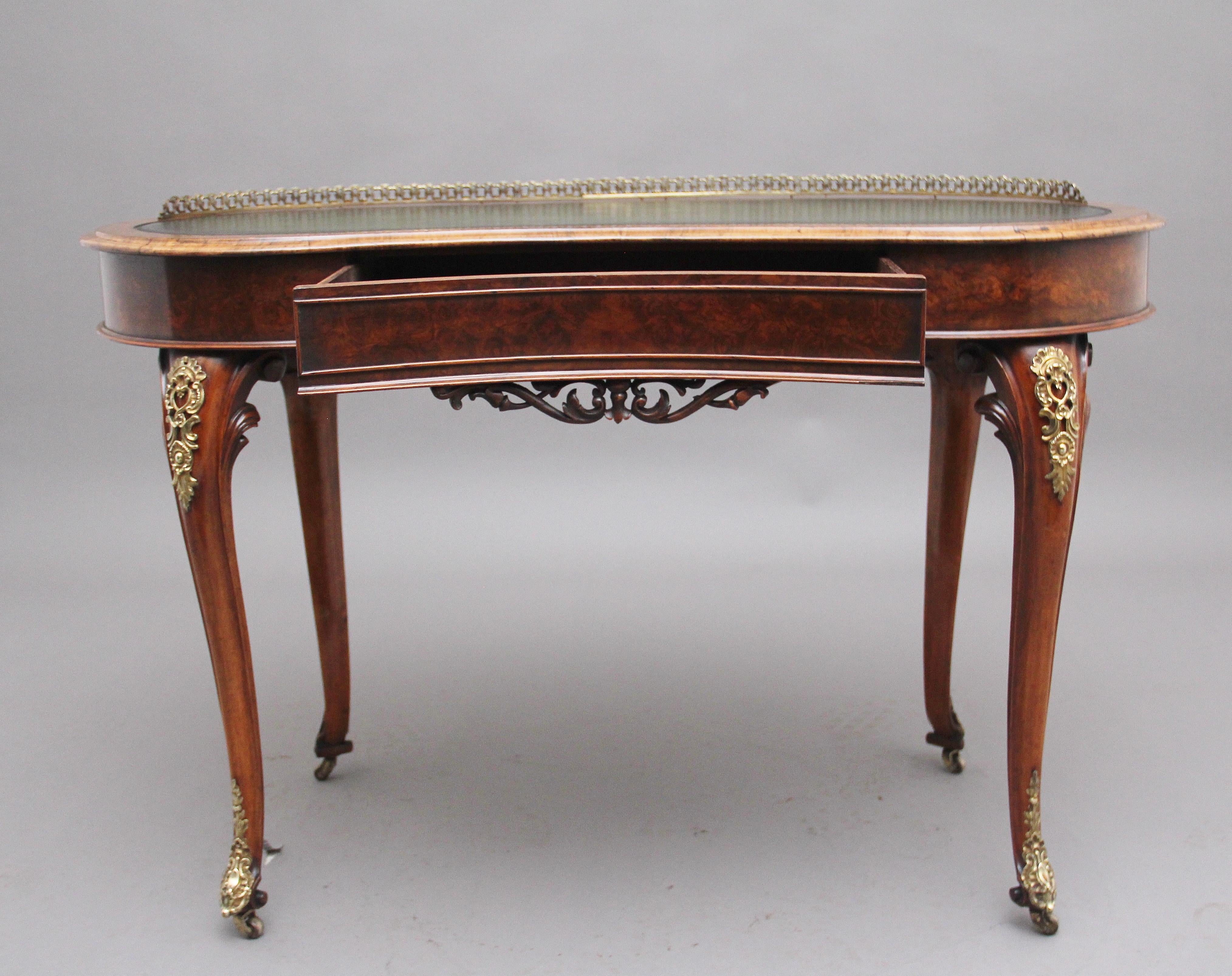 19th Century burr walnut writing table, having a moulded edge kidney shaped top with a green leather writing surface decorated with blind and gold tooling, the back of the top having a pierced brass gallery, the frieze below having a single mahogany
