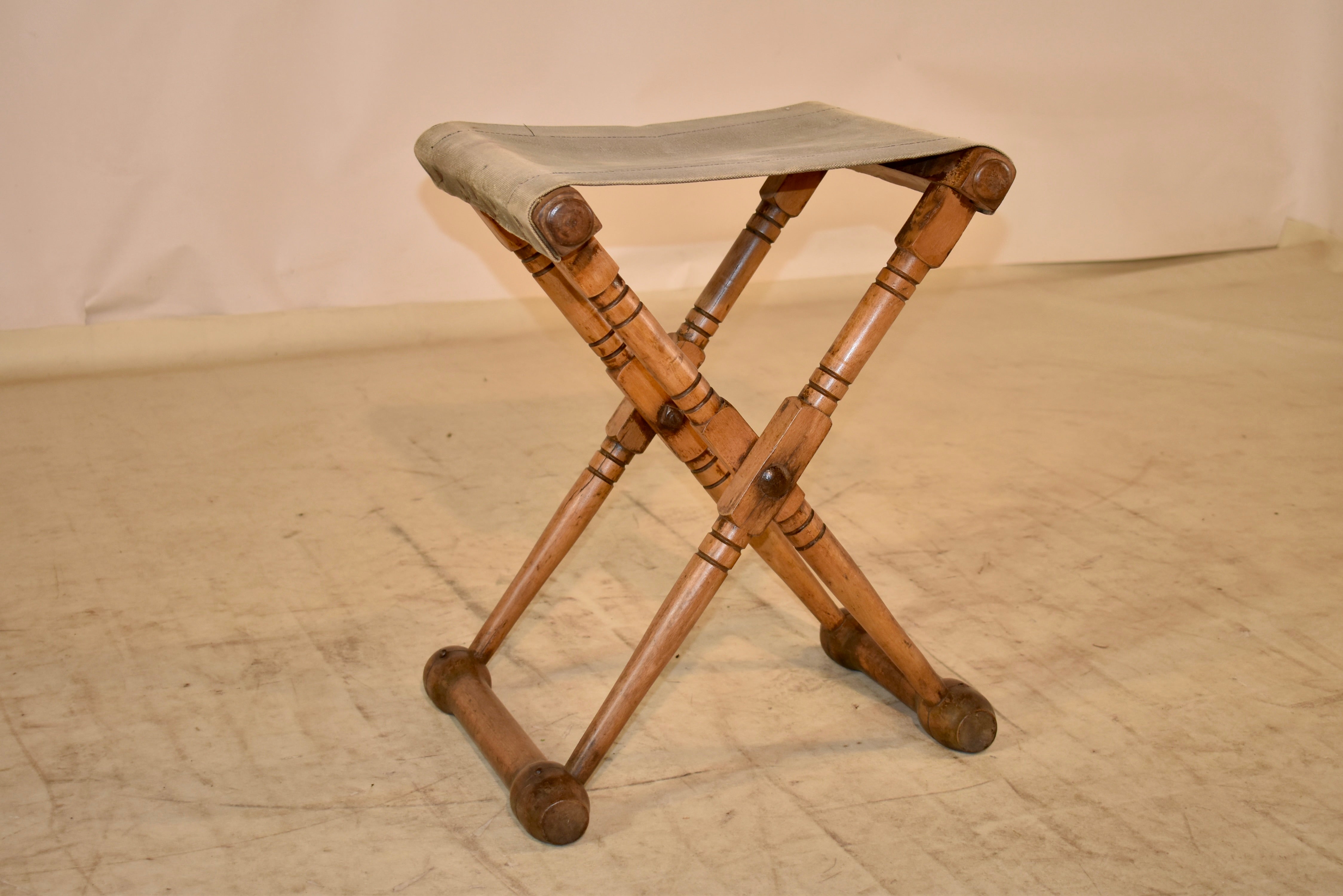 Klappbarer Campaigner-Hocker aus Obstholz aus dem späten 19. Jahrhundert mit einem gut gebrauchten Sitz aus Segeltuch.  Wunderbar in seiner Einfachheit und Nützlichkeit.  Diese Hocker sind der Inbegriff der Campaigner-Möbel, die auf dem heutigen