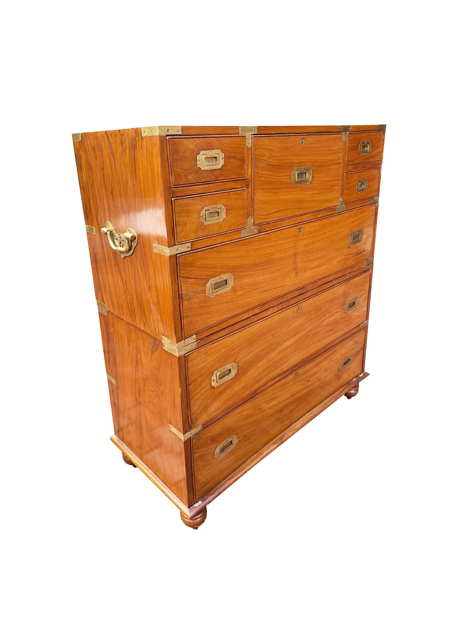 This 19th Century English Campaign chest of drawers consists of 2 case pieces hand-crafted from camphorwood with brass inset pulls, brass mounts, brass bail handles, and bun feet. The upper case has 5 small drawers atop a full-length drawer, while