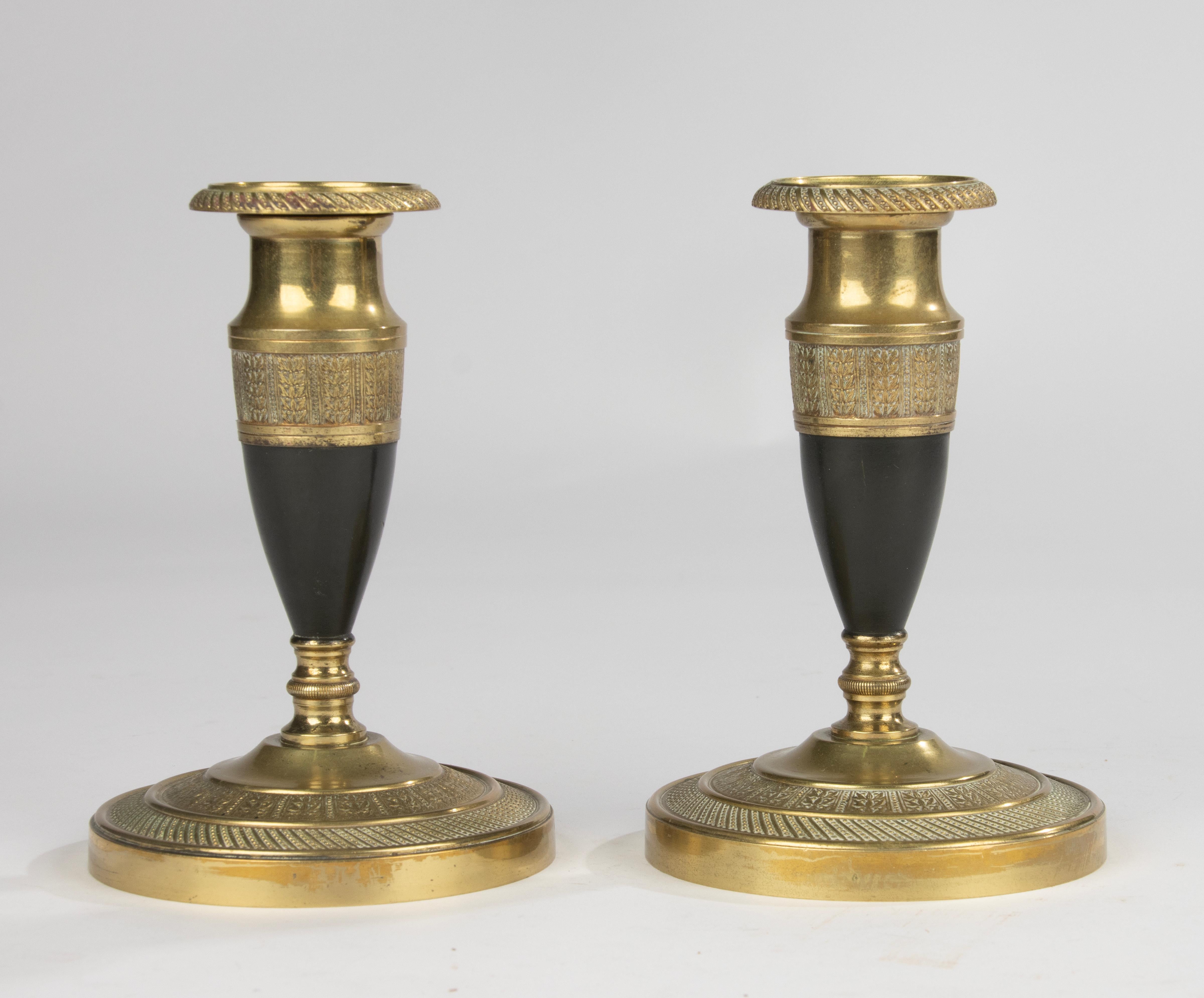 Elegant pair of French candlesticks in Empire style, circa 1880–1890.
Made of finely cast and engraved bronze with a beautiful contrast between the gilded and dark patinated sections.
The bases and upper rims are decorated with refined neoclassical