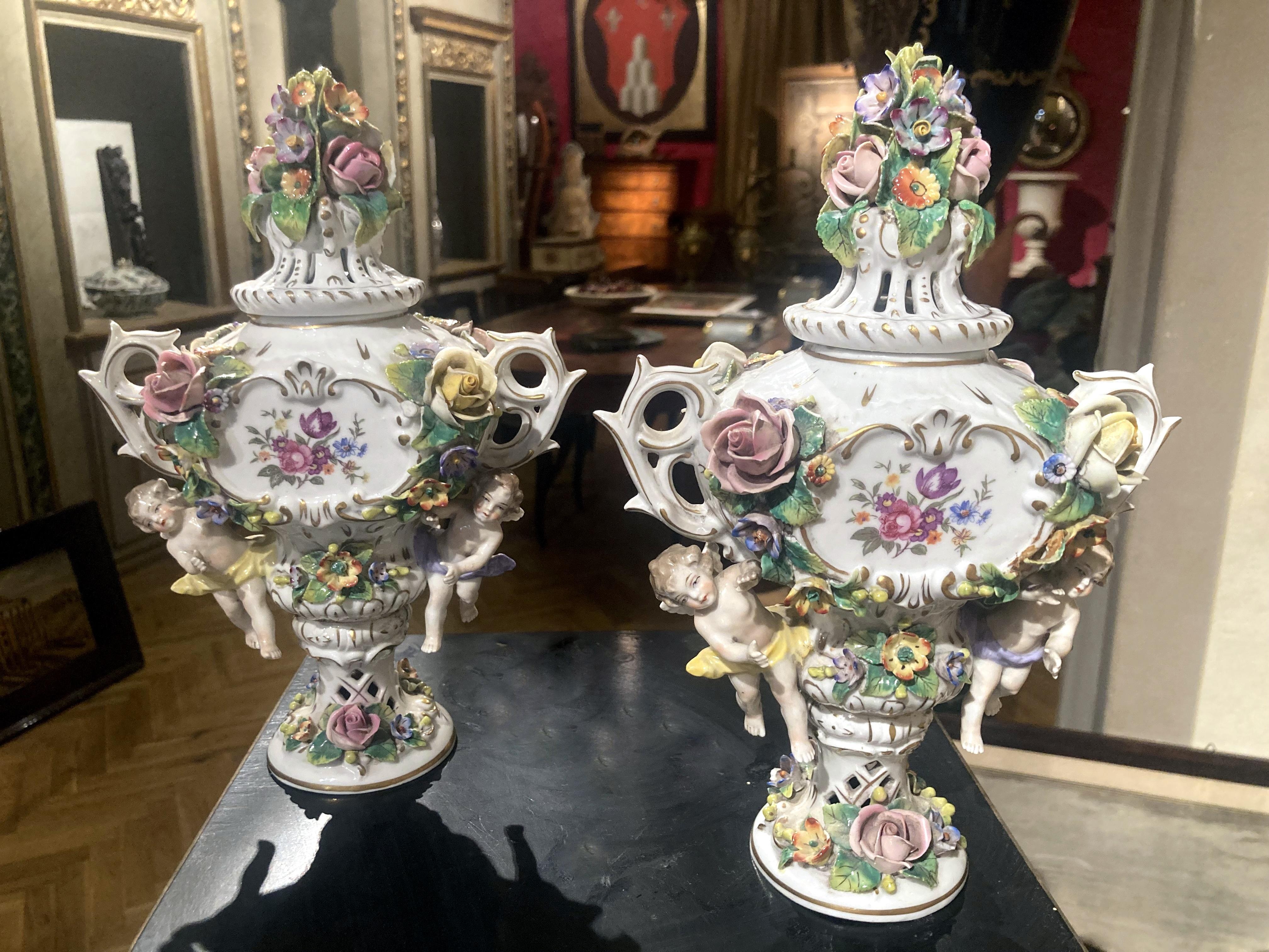 An exquisite pair of early 19th century Italian Capodimonte Rocococ style polychrome porcelain incense burners in the form of urn shaped vases with two handles and pierced lids. 
The body is centered on both sides by a flower garland painted with