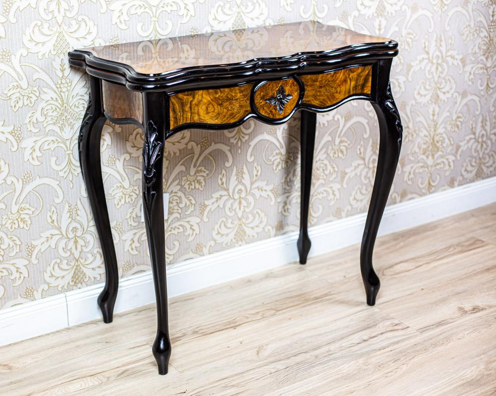 We present you a wall piece of furniture in the form of a console table with a double-sided extendable top. The whole is supported on bent legs.
The top is composed of two section which are connected with hinges.
It can be rotated around an