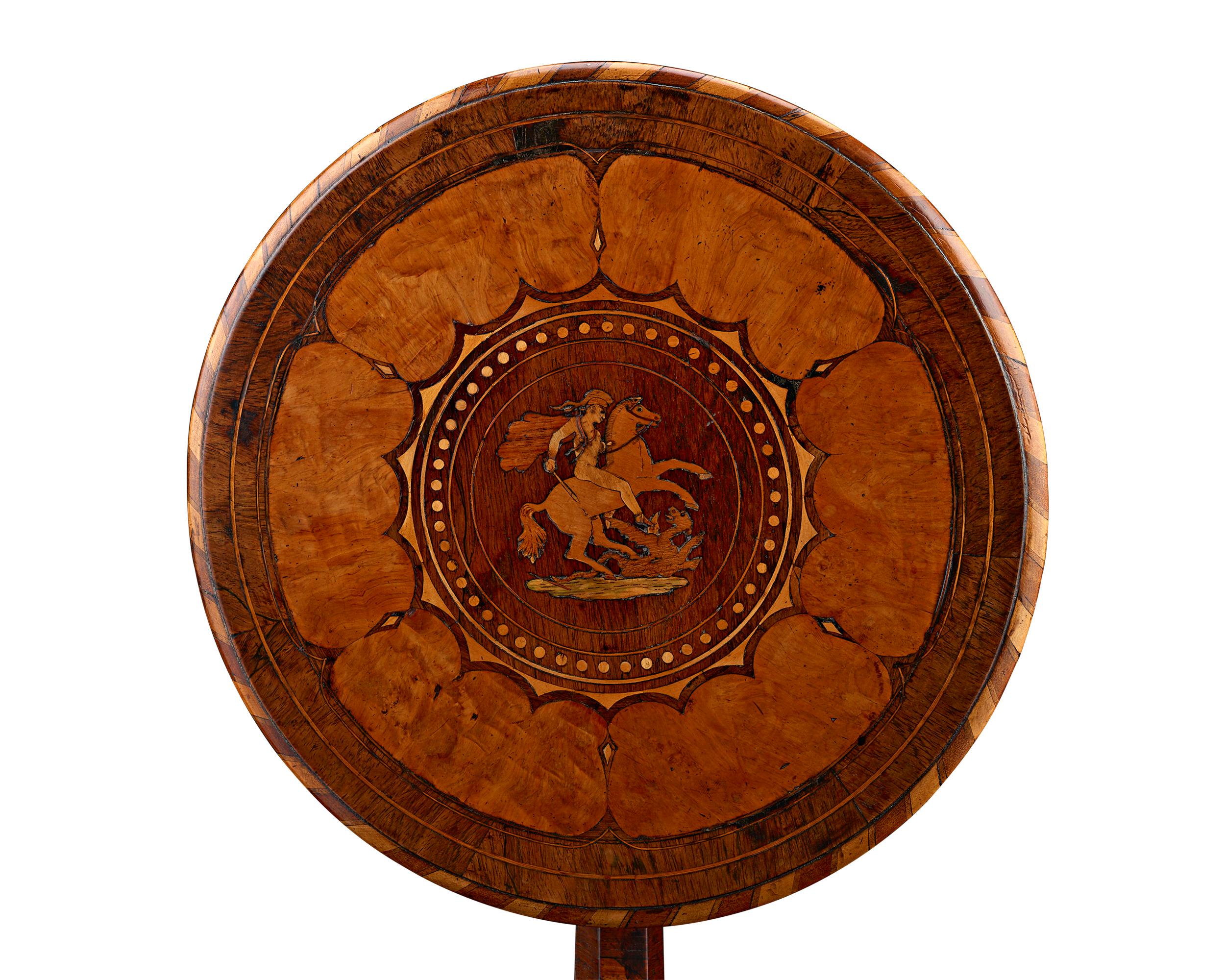 Elegance and artistry distinguish this stunning tilt-top marquetry table hailing from the Caribbean island of Grenada. Crafted from veneers native to the West Indies and South America, the table features the inlay of St. George slaying the dragon,