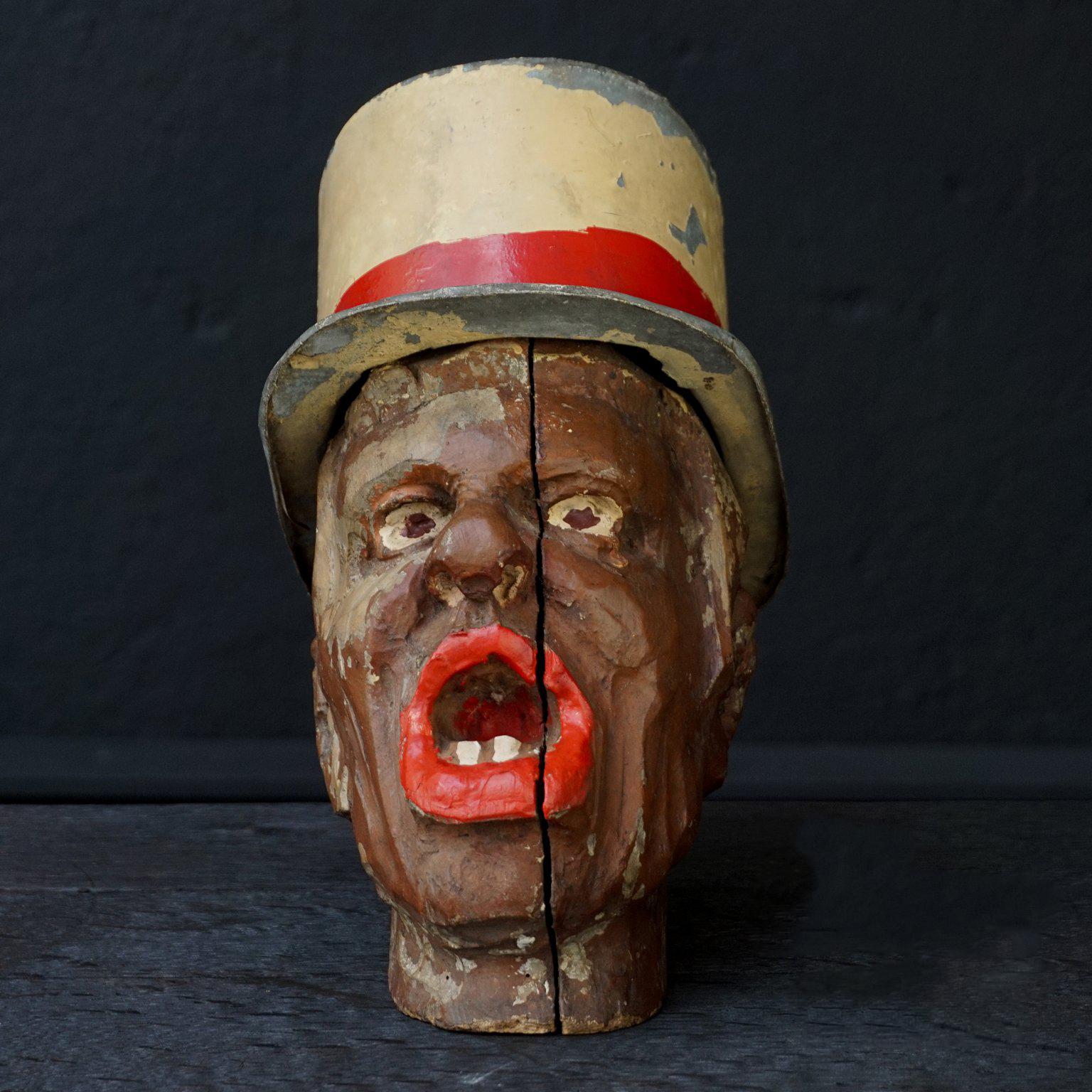 This head is from a fair or carnival game.
Not sure what the game was, perhaps the head has been used to toss rings over, or maybe you were supposed to throw something in his mouth. His hat does not come off, so it probably was not a Charlie's hat