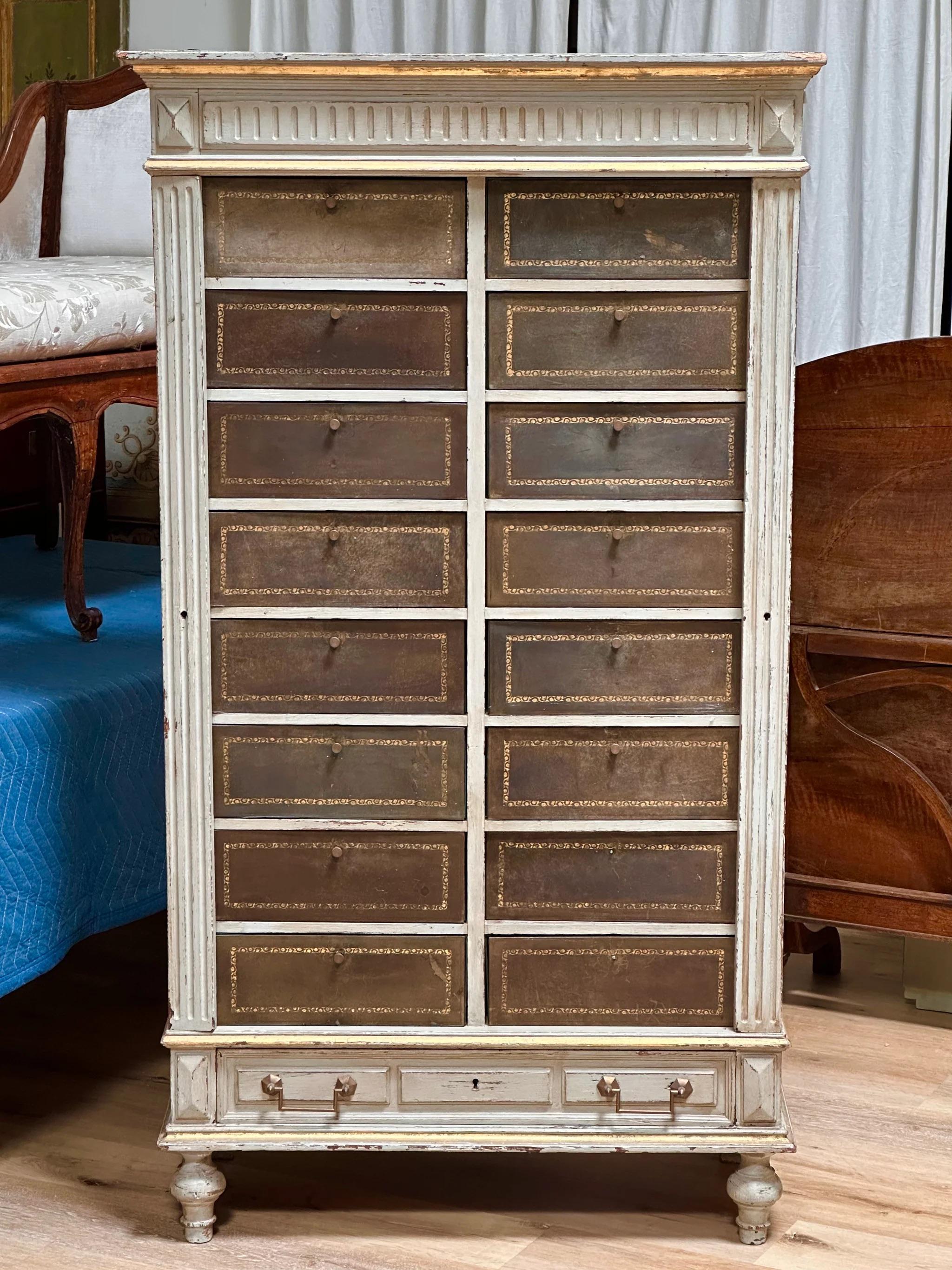 Cartonnier, cabinet, likely French or Swedish, 19th century, stepped ogee cornice over a fluted and blocked frieze, fluted side locks enclosing a bank of tooled leather clad cartonnier drawers, paneled base drawer, toupie feet, 65 x 36-1/4 x 15 in.

