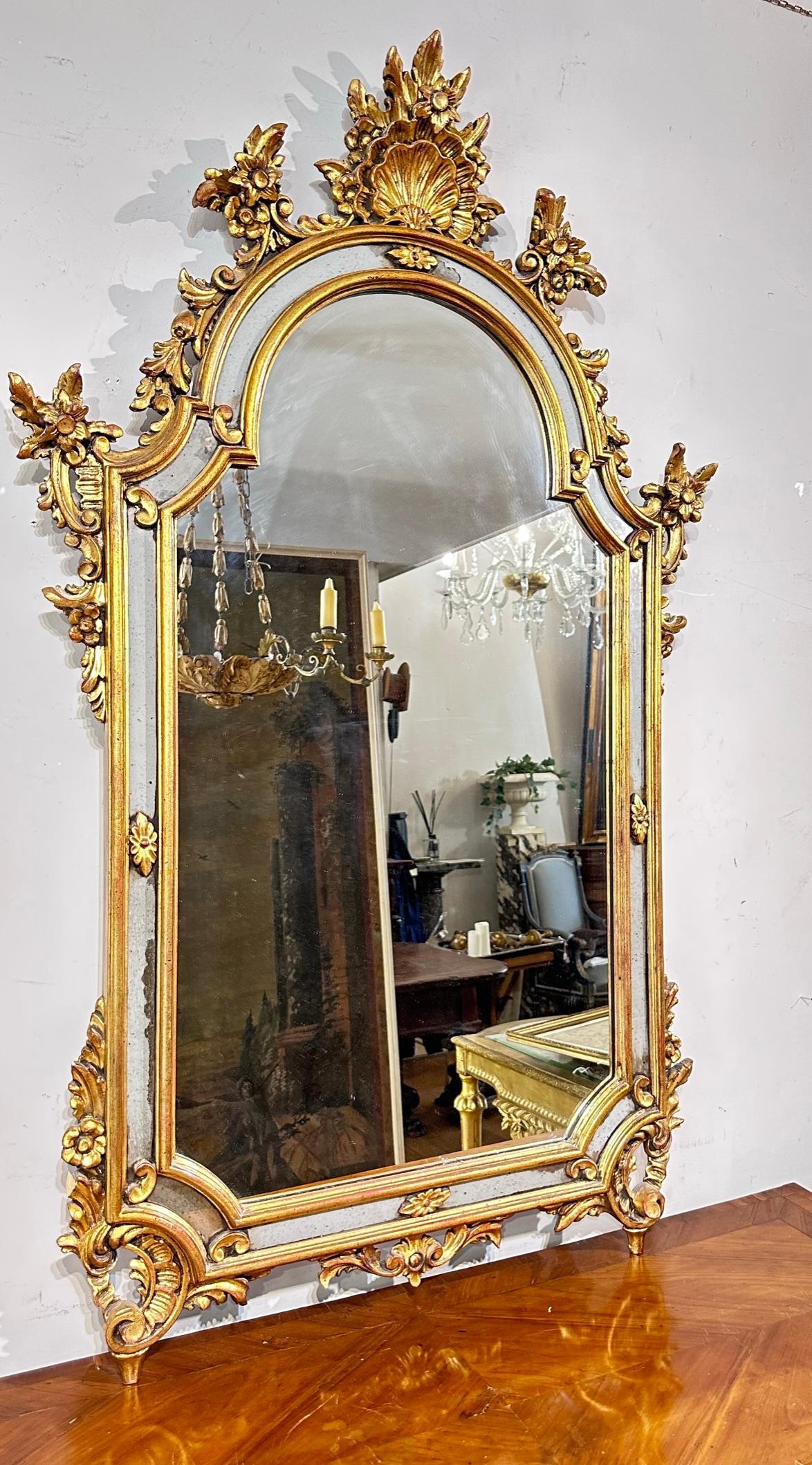 Elégant miroir en bois sculpté et doré avec encadrement floral et coquillage. La partie centrale est en miroir. Le cadre comporte également des inserts de miroir. Fabrication italienne de la seconde moitié du XIXe siècle.

Dimensions HxLxP 130 x 82